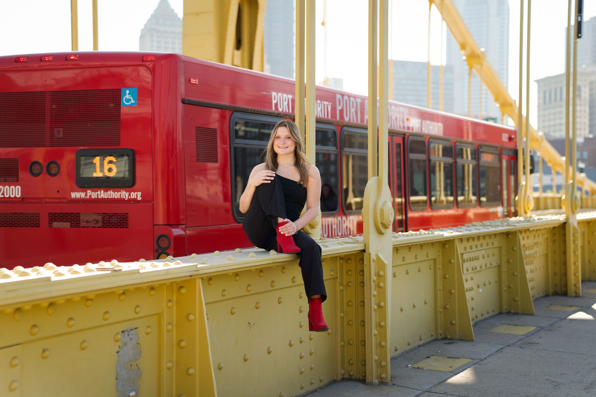 Urban portrait on yellow bridge with red streetcar in background.