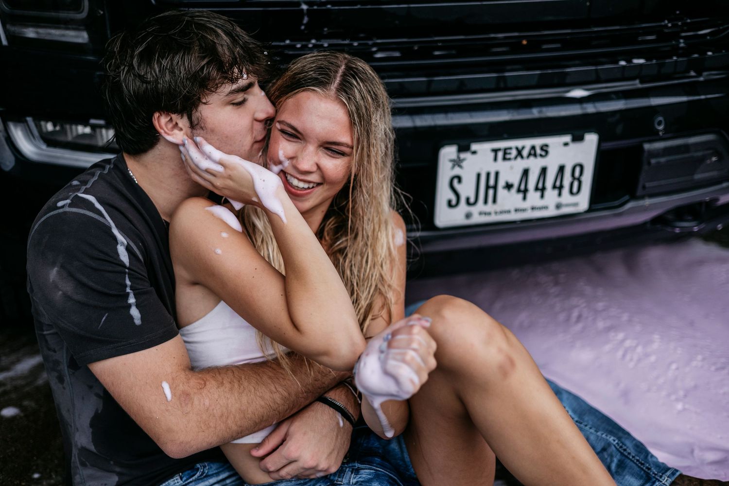 A playful couple shares an intimate moment near a pickup truck.