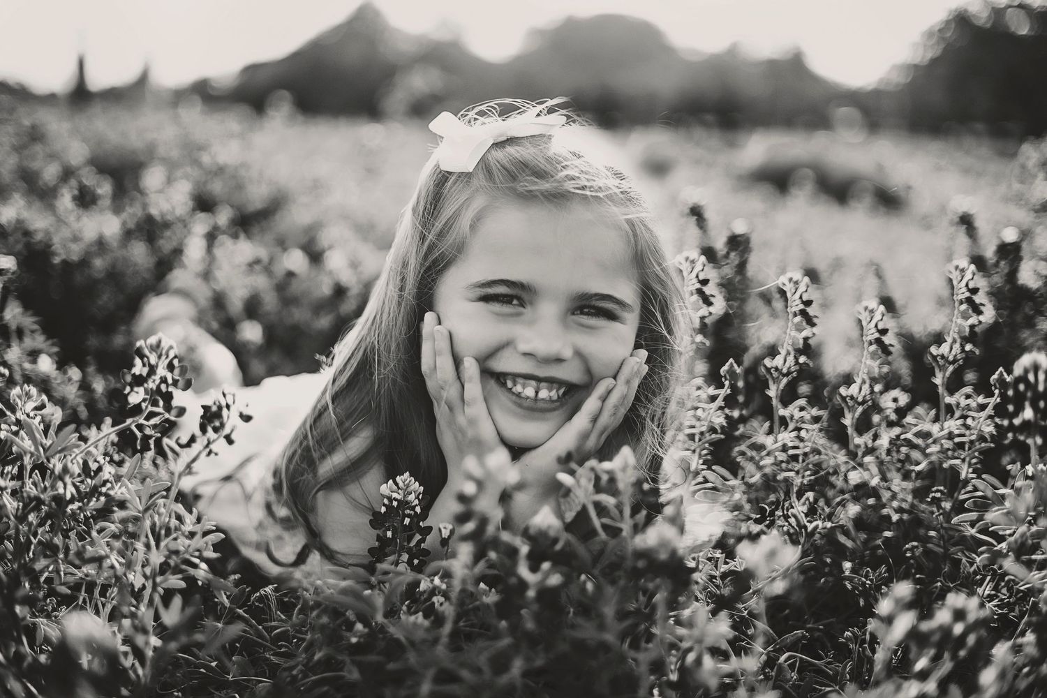 A black and white portrait captures joy among wildflowers in a field.