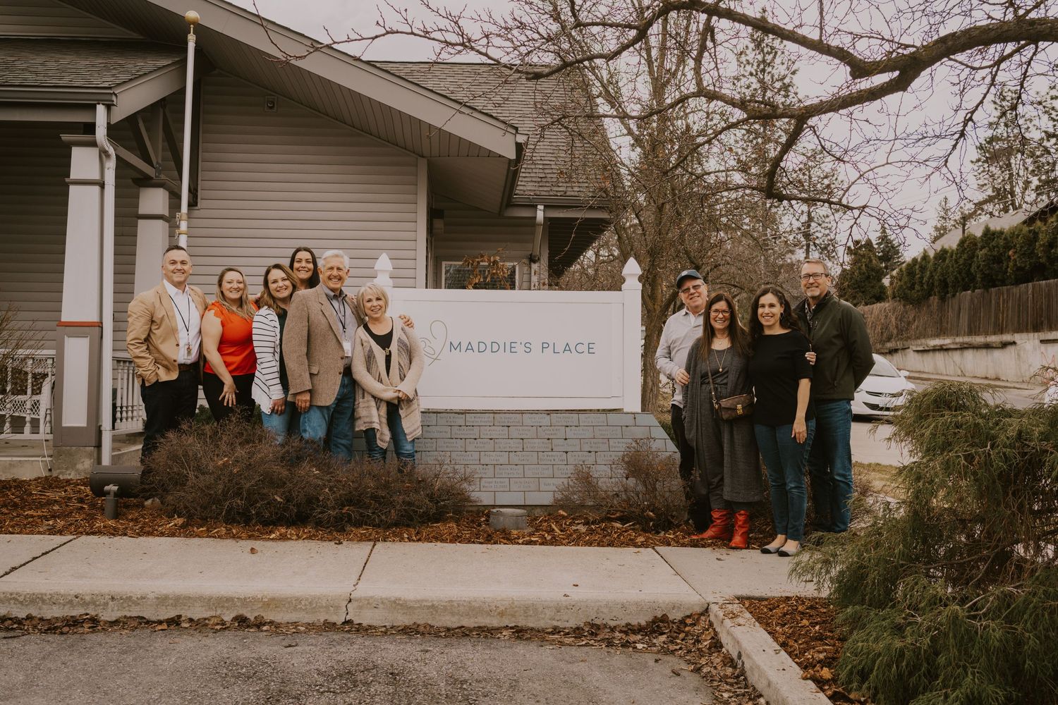 Group of people gathered outside a modern building entrance on a cloudy day.