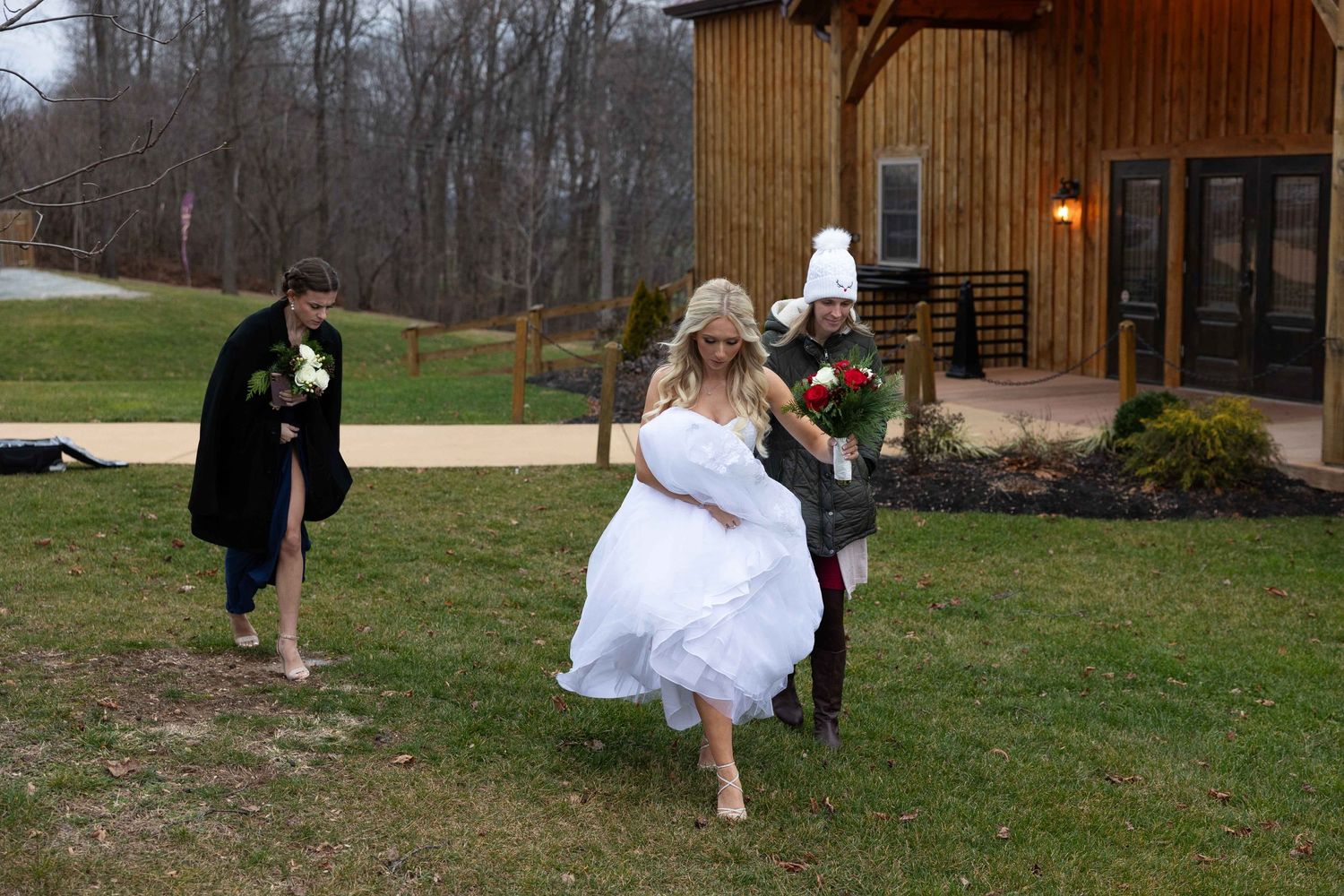 Wedding celebration outdoors near a rustic wooden barn on a winter day.