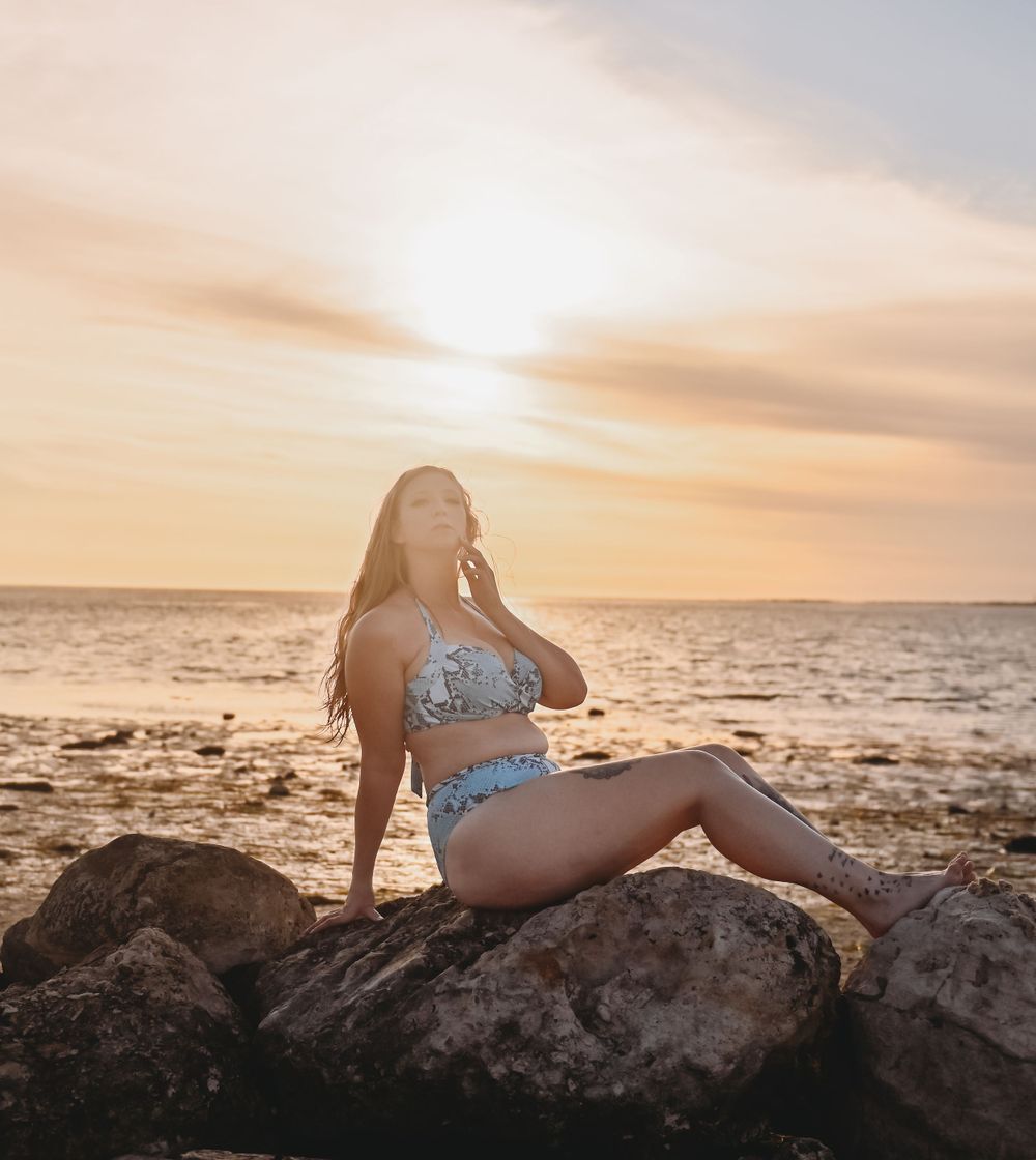 Sunset beach portrait on rocky shore with warm golden light and ocean view.