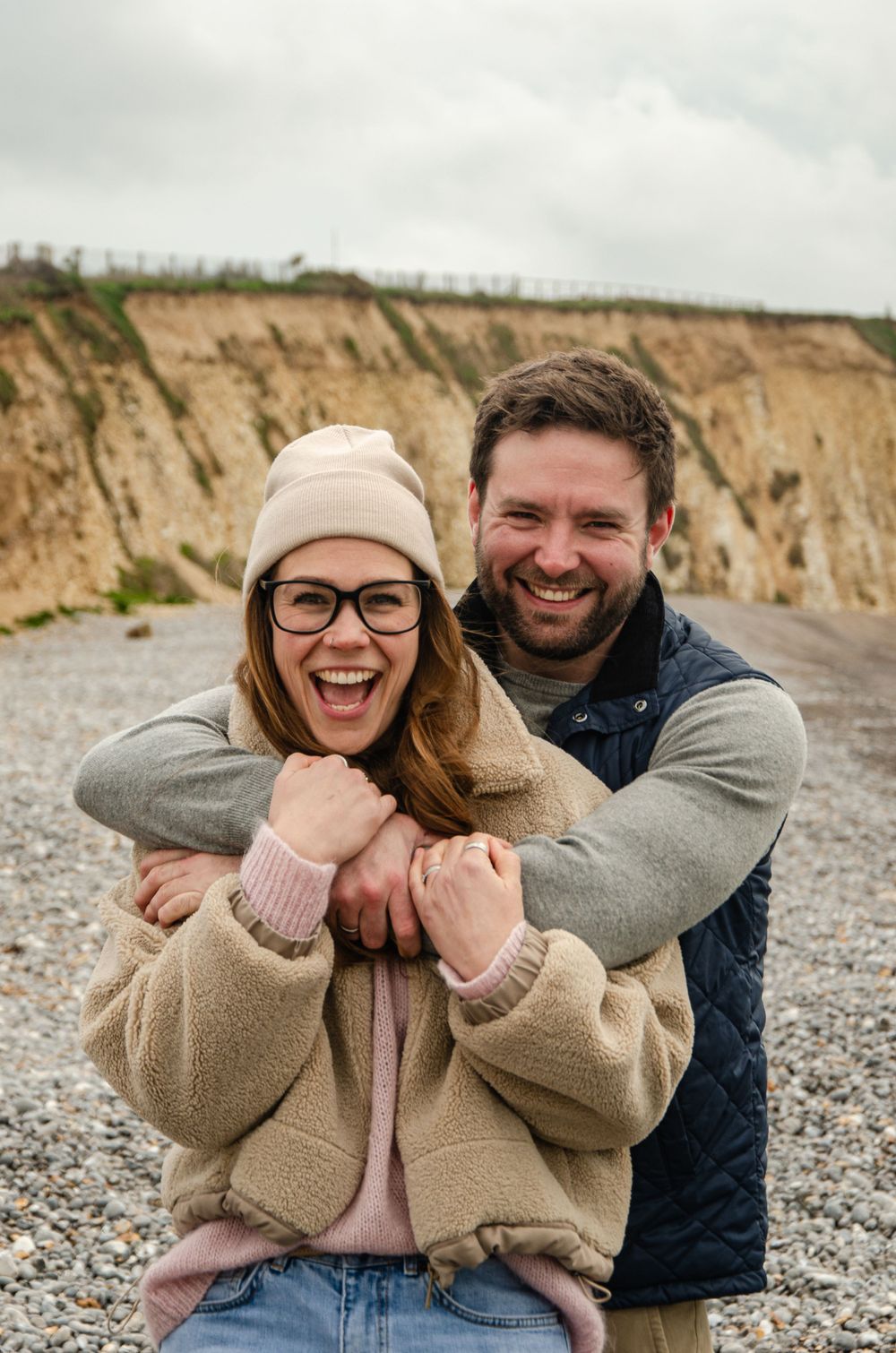 young couple at the beach in Spring hugging and laughing