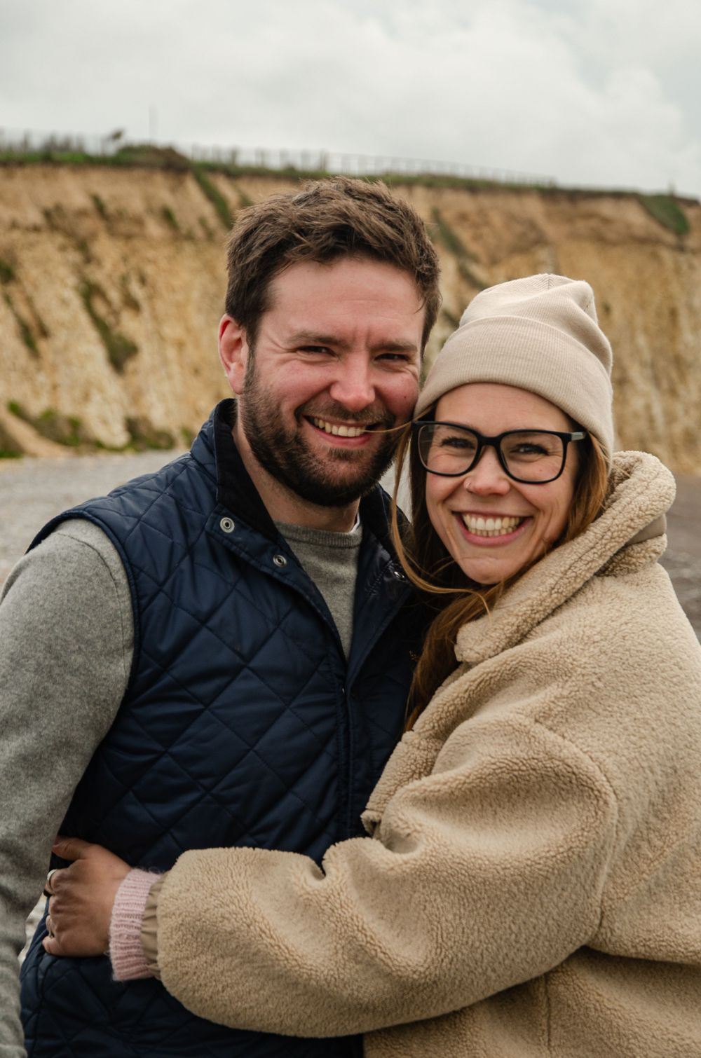 young couple at the beach in Spring hugging and laughing