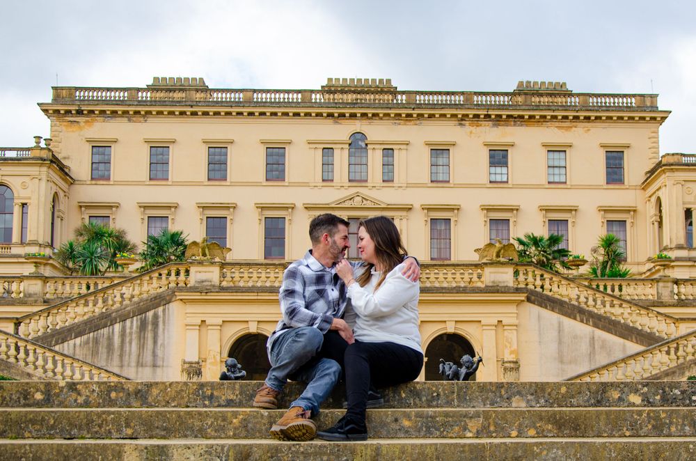Couple sitting on grand stone steps of historic building during photoshoot.