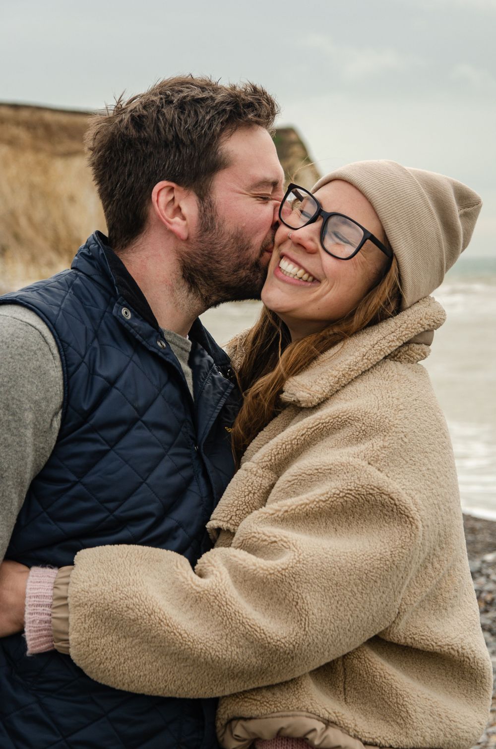 young couple at the beach in Spring hugging and laughing