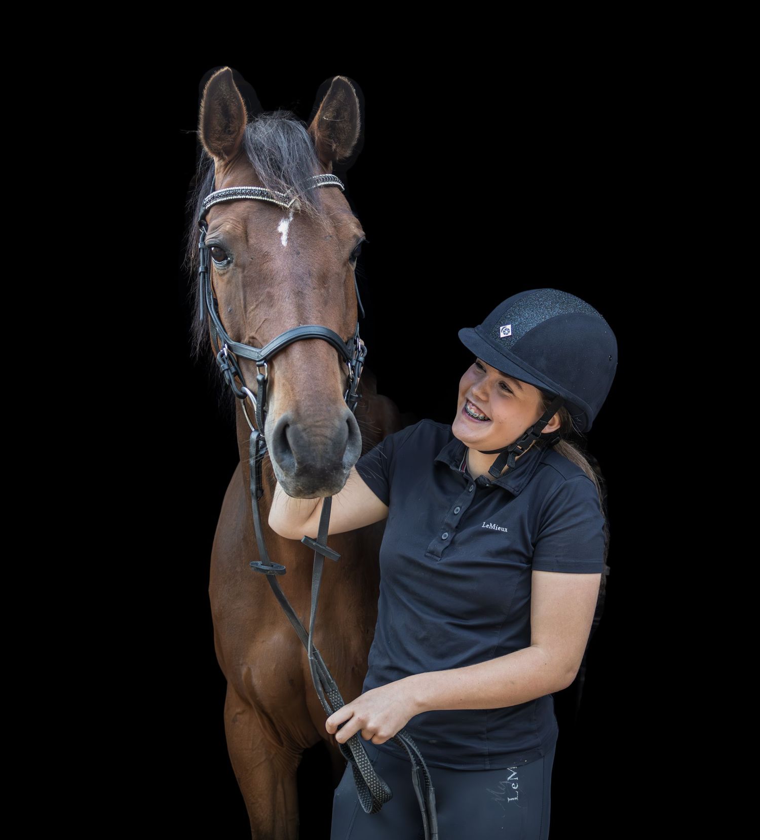 A bay horse and rider share a close moment against a dark background.