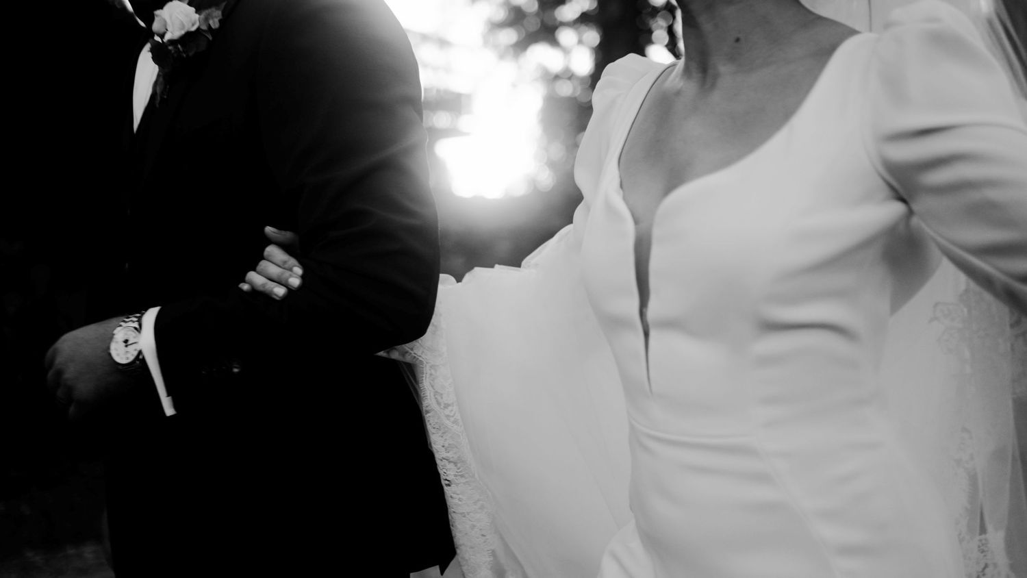 High contrast black and white photo of bride and groom in intimate moment with sunburst.