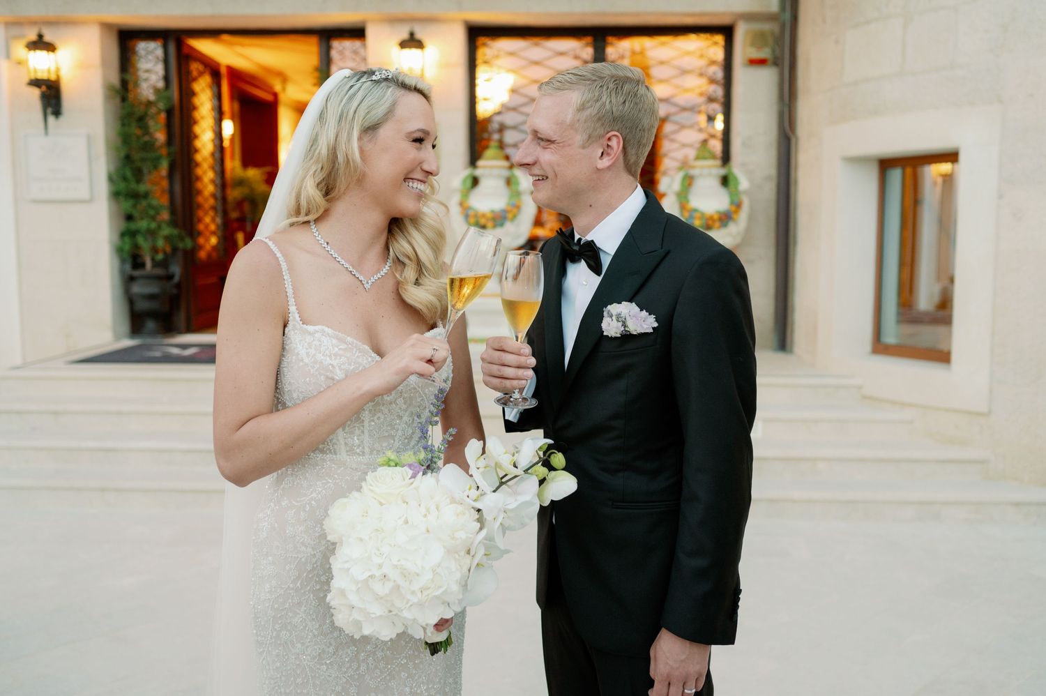 Newlyweds share intimate moment while toasting with champagne glasses.