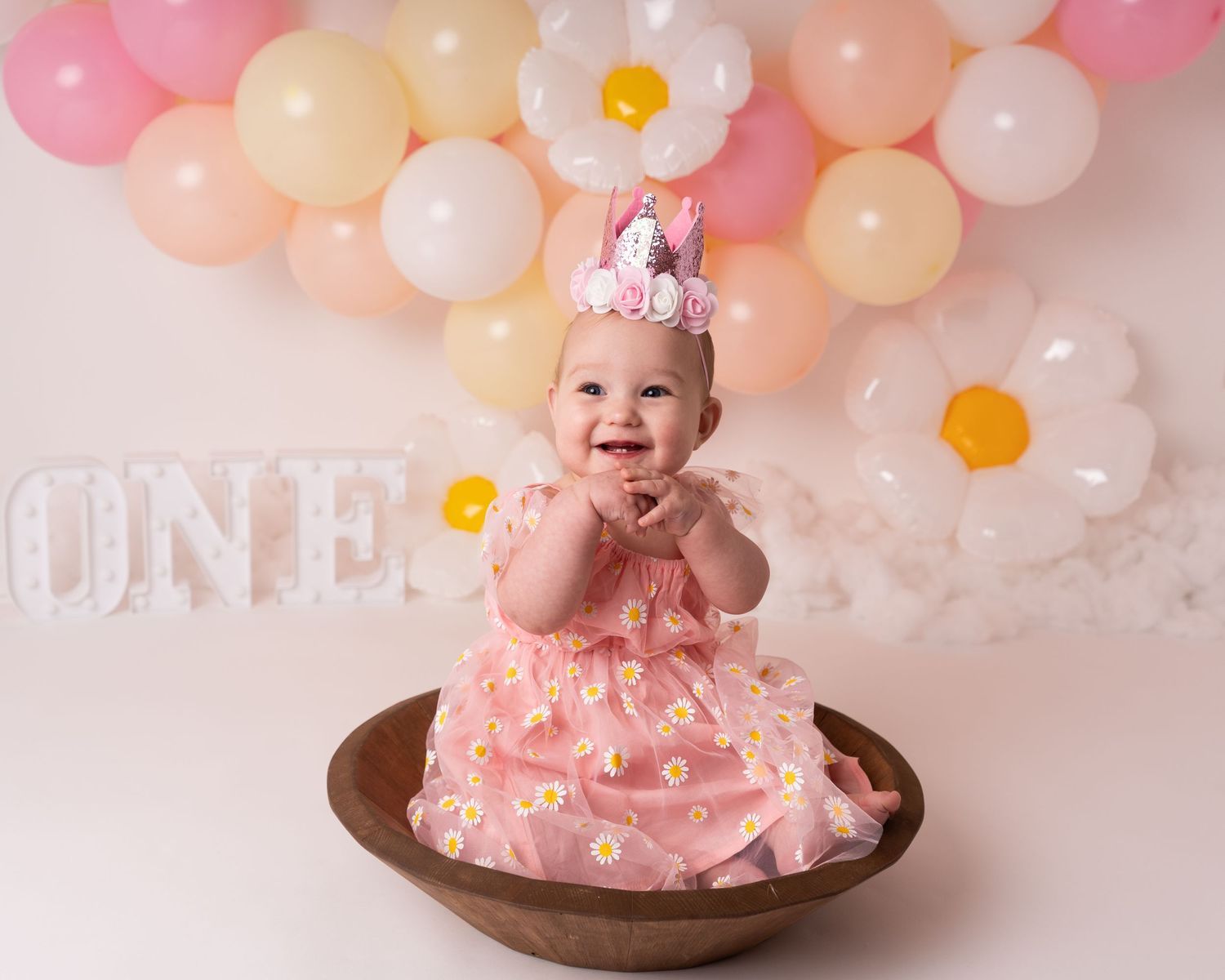 cute baby girl one year old at first birthday cake smash pastel balloons and daisies client of Heather Katie Photography