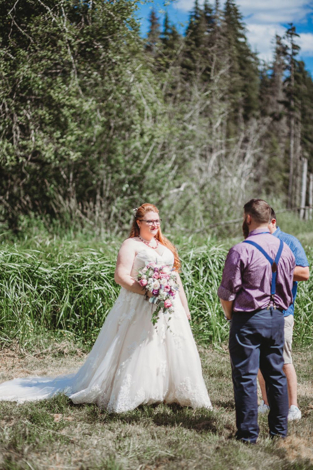 Bride and groom say their vows in a meadow in front of a very large mountain