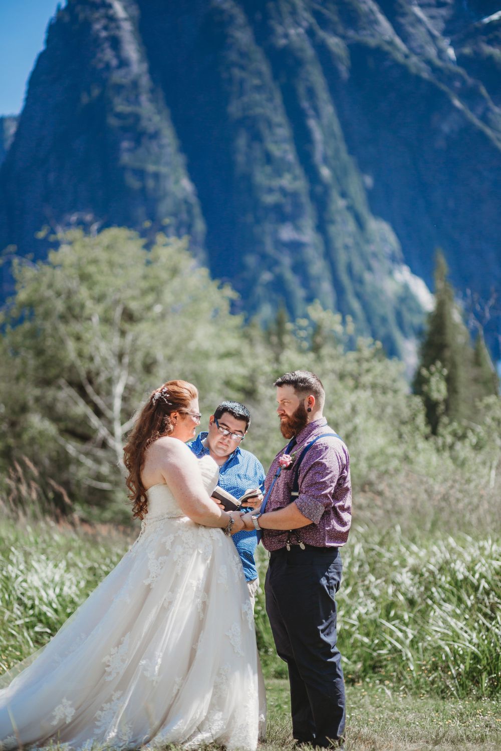 Bride and groom say their vows in a meadow in front of a very large mountain