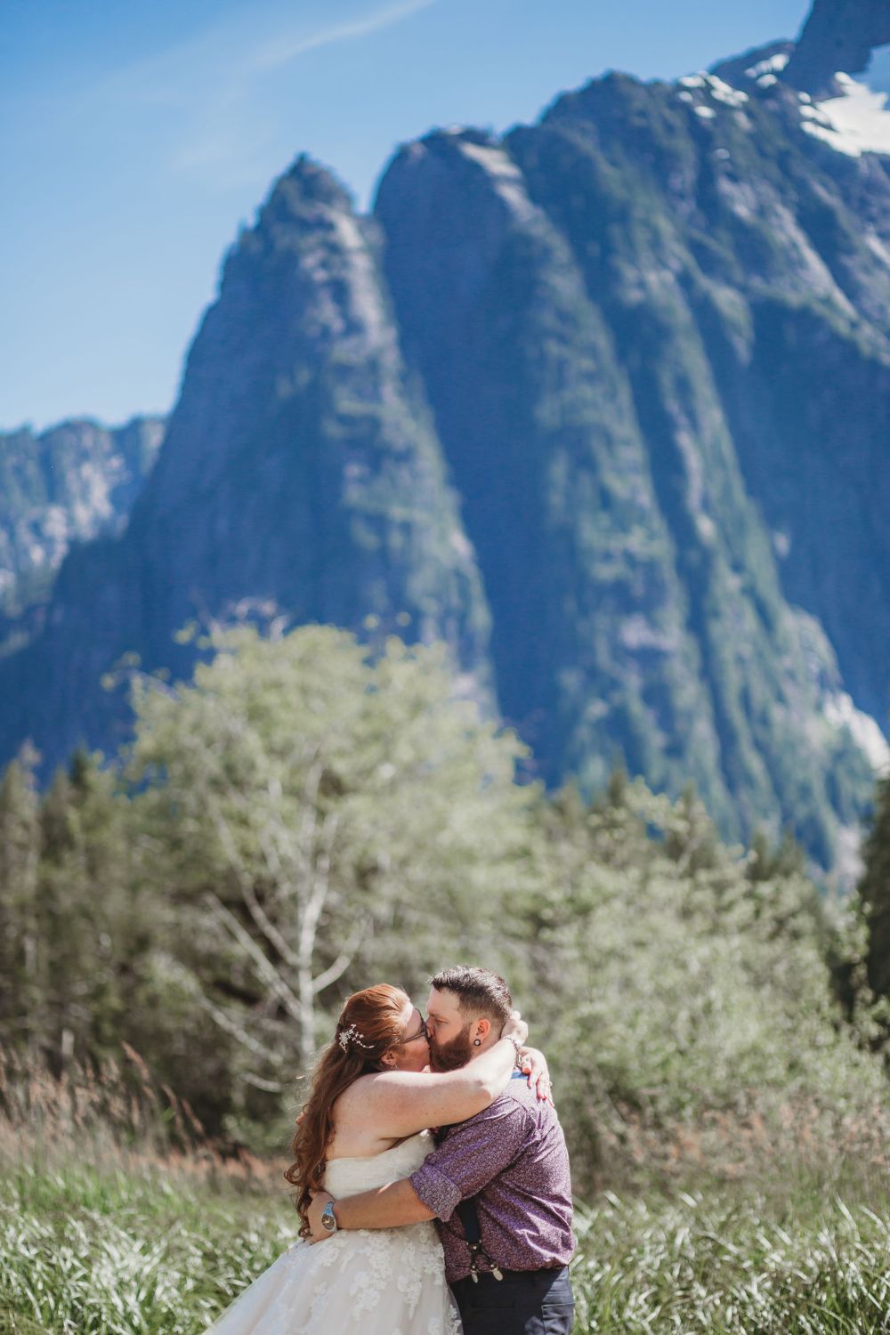 Bride and groom say their vows in a meadow in front of a very large mountain
