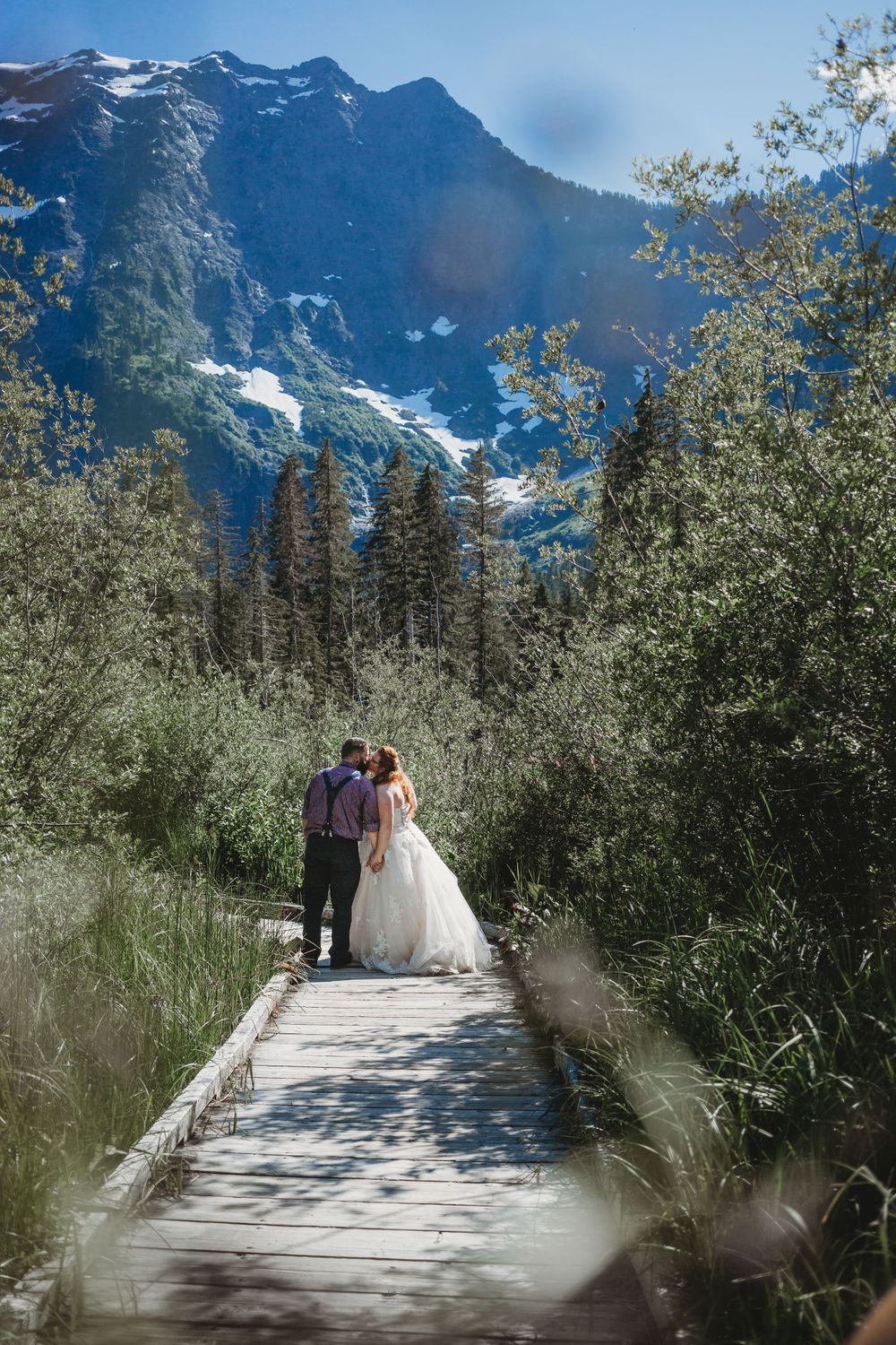 Bride and groom kiss on a boardwalk in the mountains after their elopement
