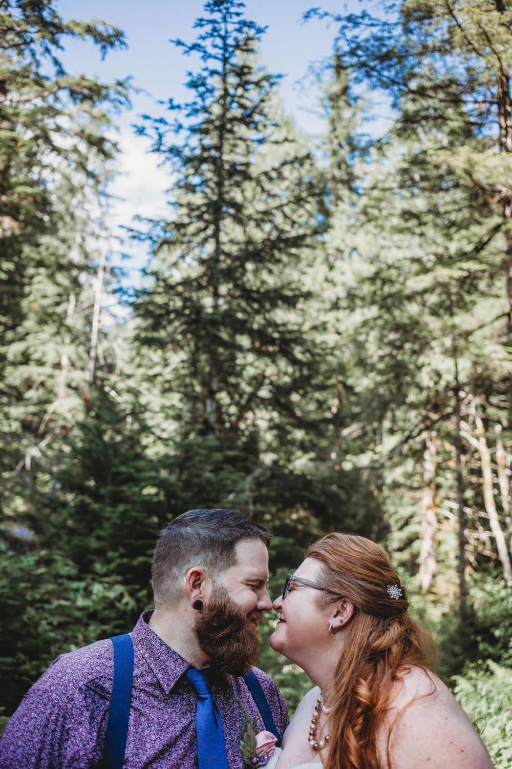 Bride and groom rub noses and laugh in the trees at their elopement