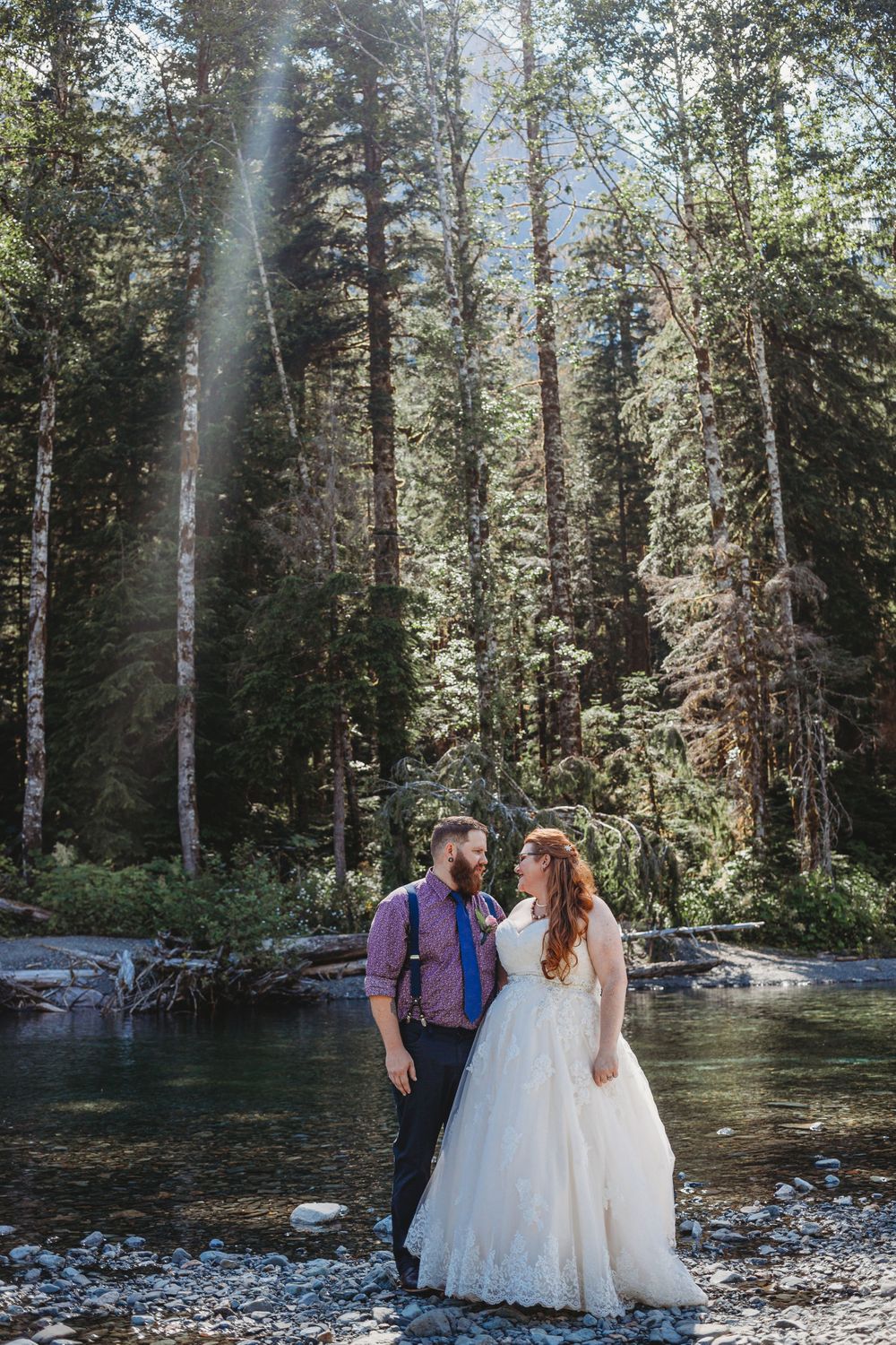 Bride and groom standing along the river at their mountain elopement