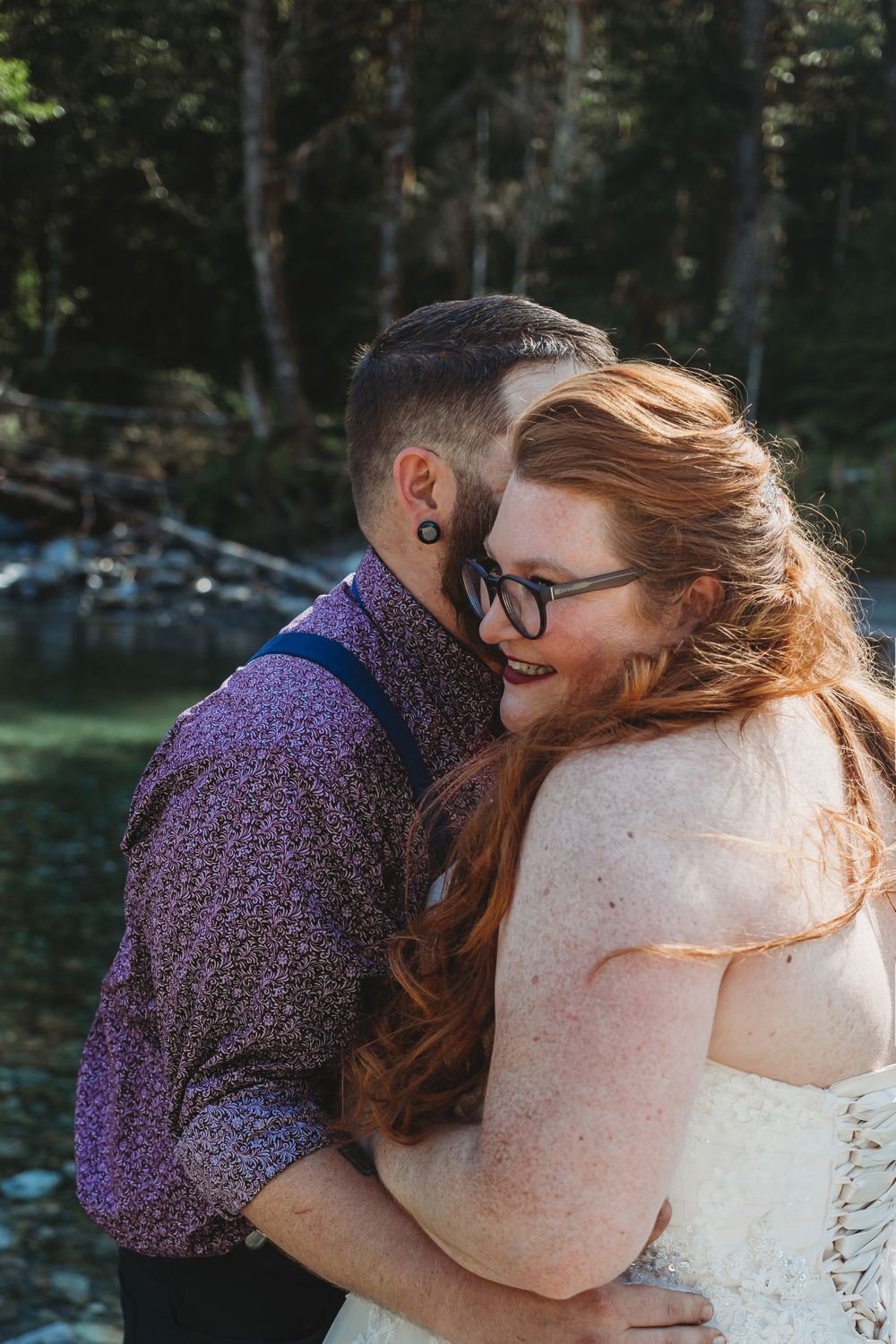 Groom whispers in his brides ear along the riverside.