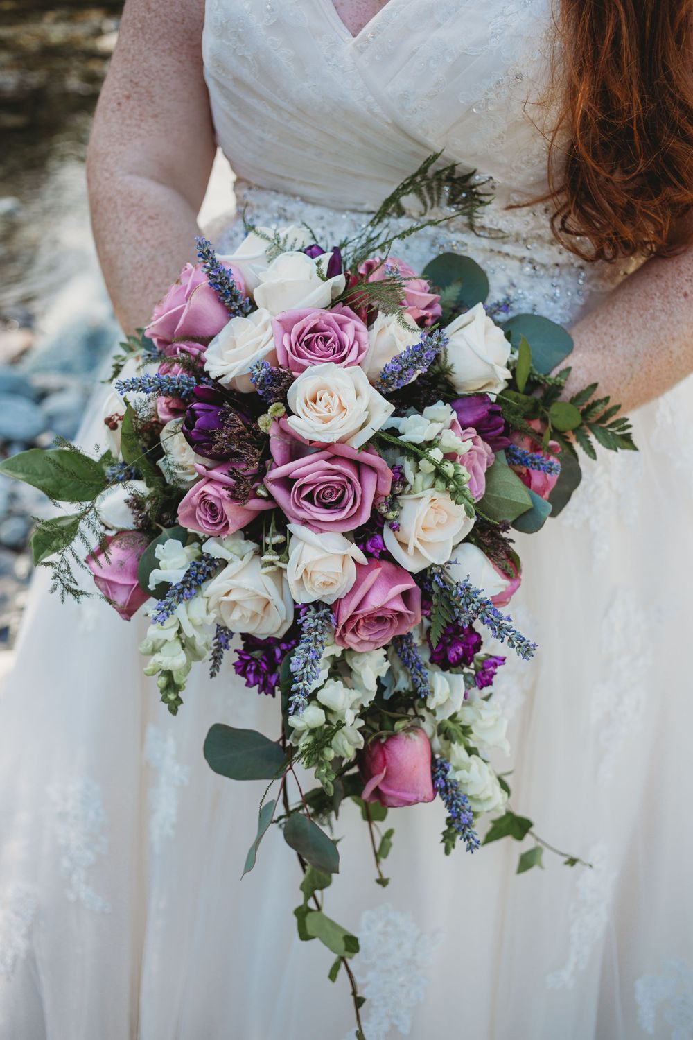 A close up of a beautiful bouquet with white and purple roses with greenery