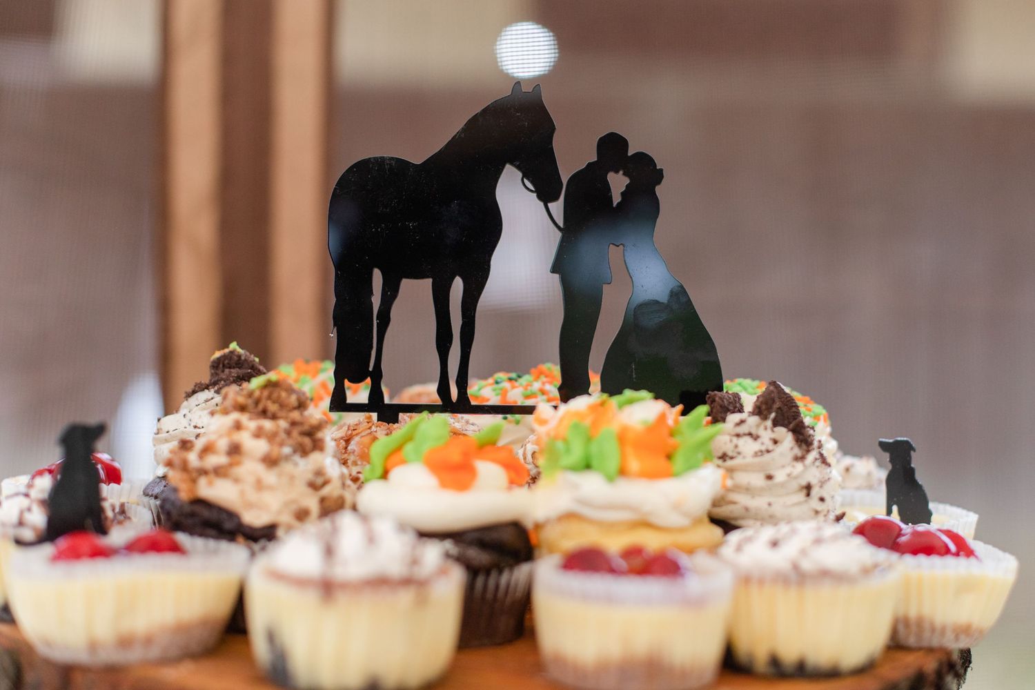 Rustic cupcake display with decorative horse silhouettes on wooden stands.