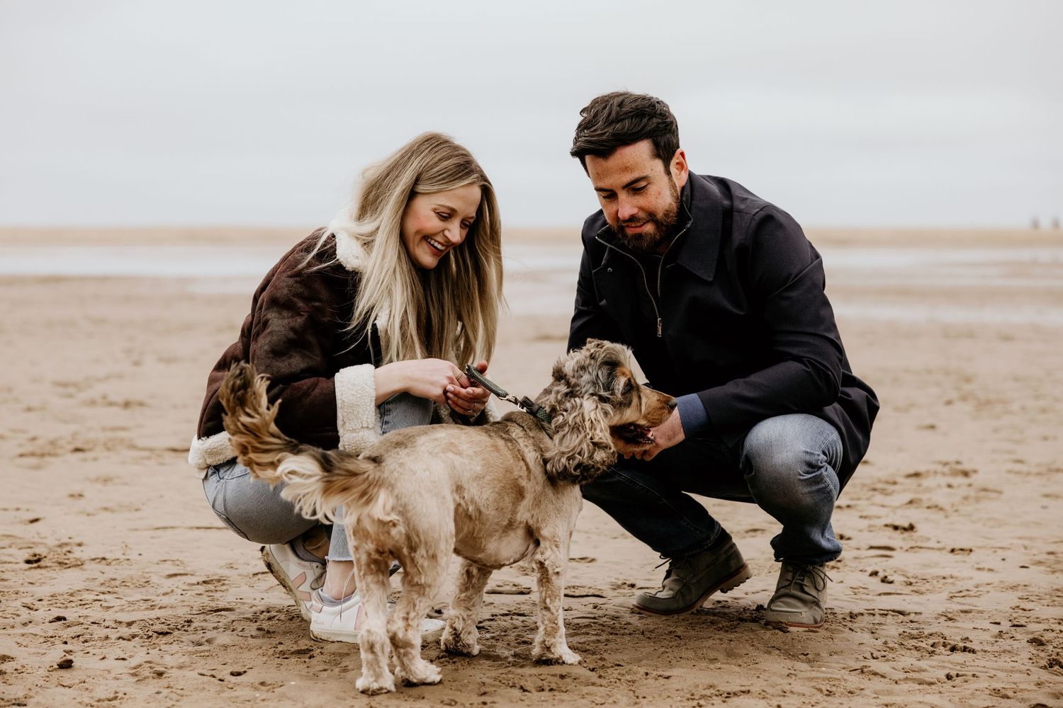 couple with spaniel on the beach