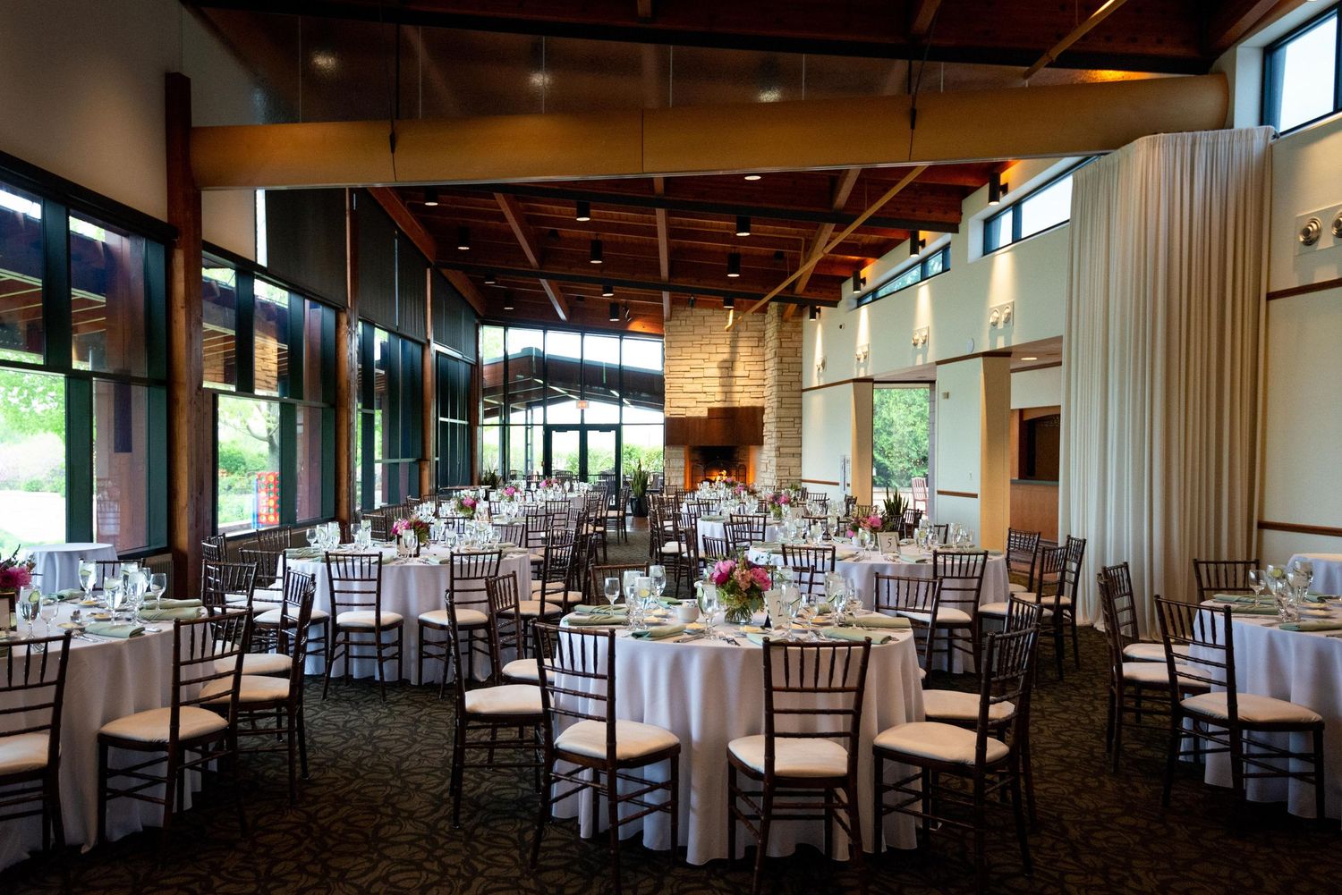 Long banquet hall with wooden beams and tables set for a wedding reception.