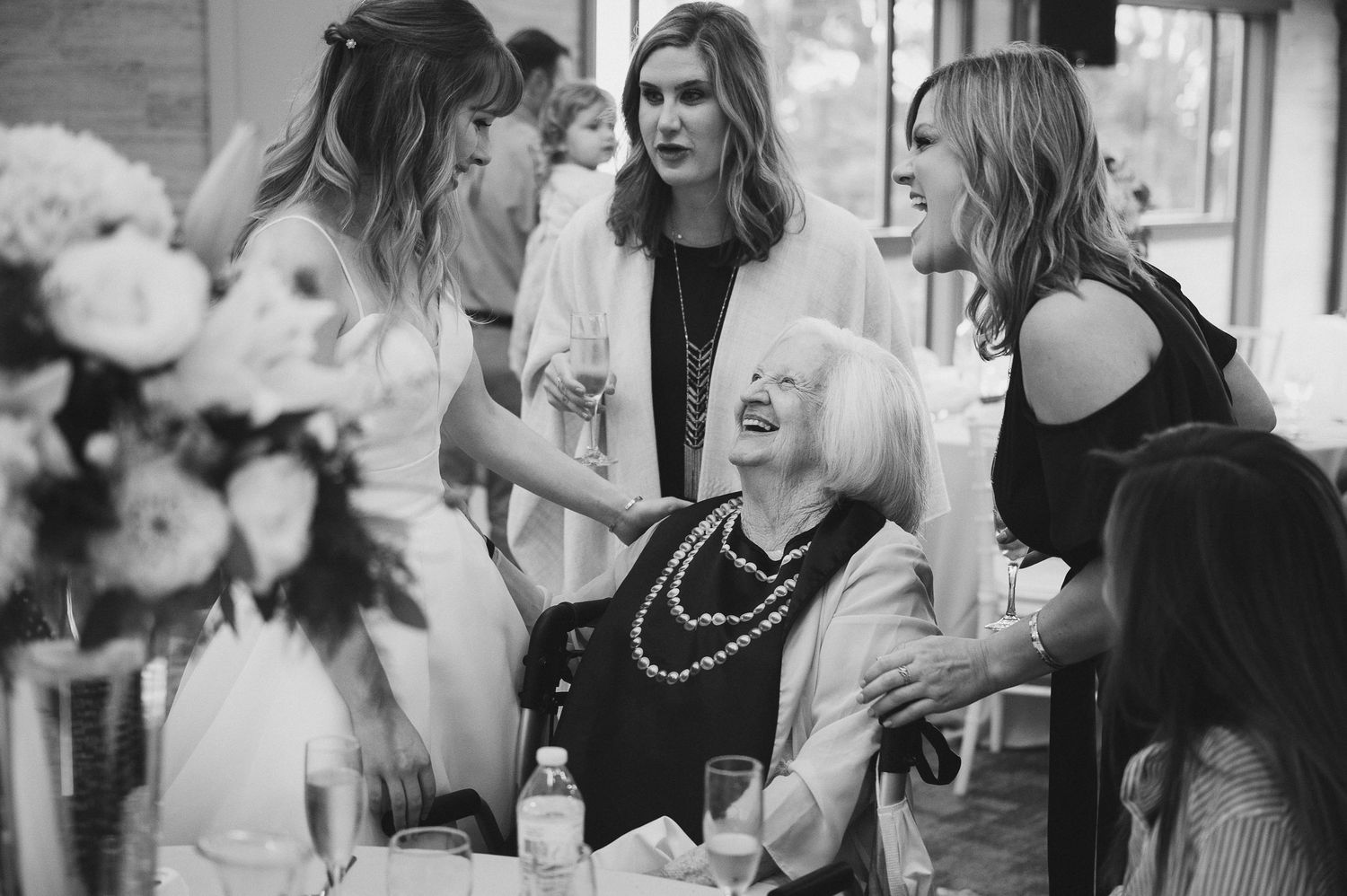Black and white photo of wedding celebration with multiple generations gathered around table.