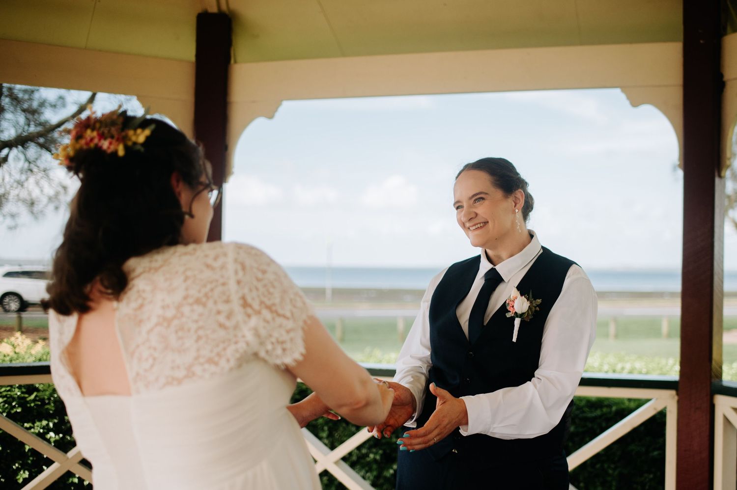 Two people holding hands during an intimate wedding ceremony under a gazebo.