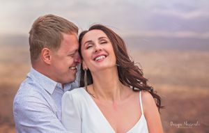 Romantic desert portrait with soft sunset lighting and mountain backdrop.