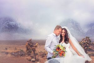 Desert wedding portrait with misty mountains and desert flora creating a dramatic backdrop.