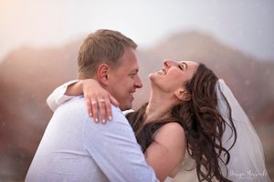 A candid wedding moment showing pure joy against a desert mountain landscape at sunset.