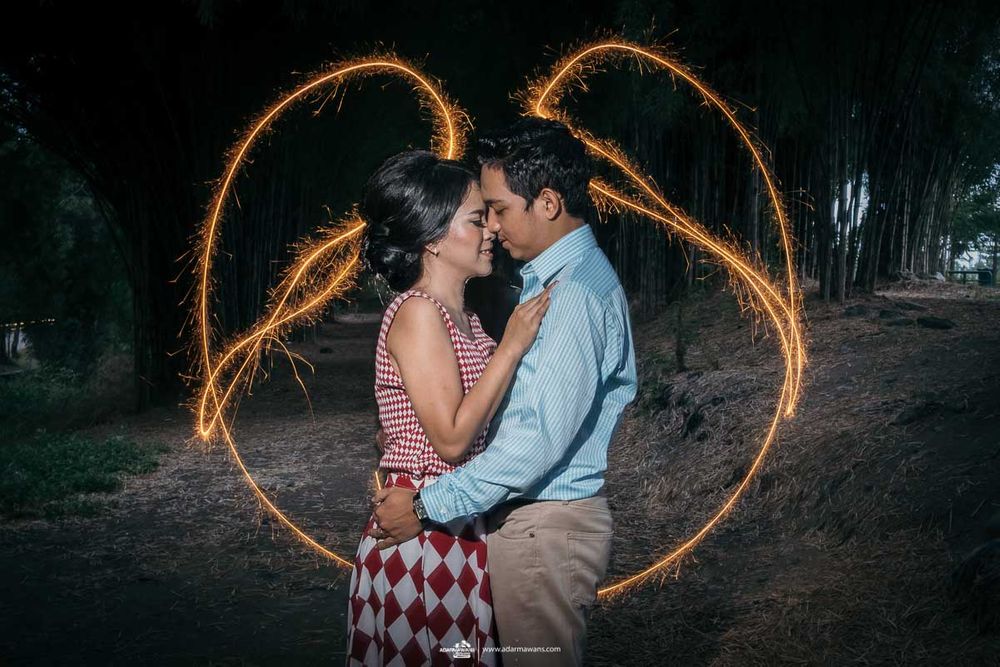 A romantic couple embracing with a heart-shaped light painting effect in the background.