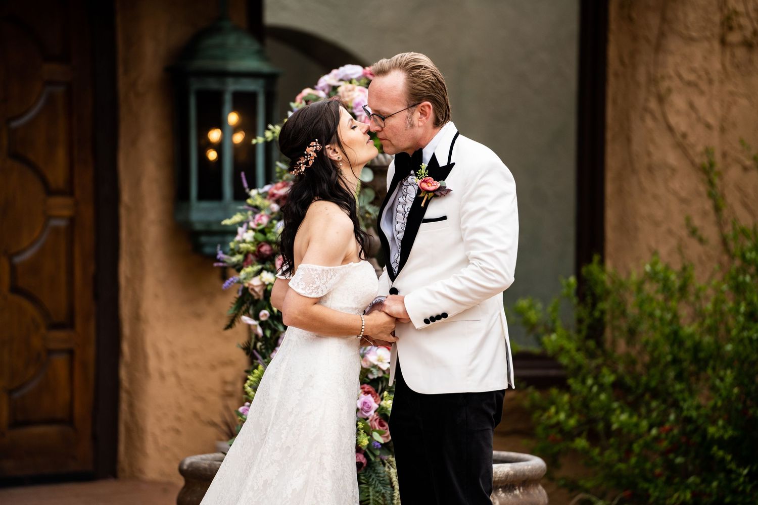 Romantic wedding moment captured outside Spanish-style villa with ornate door.
