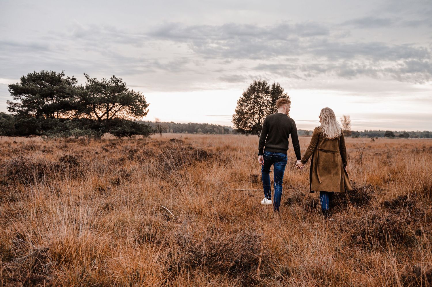 Family members walking hand in hand across scenic autumn landscape.