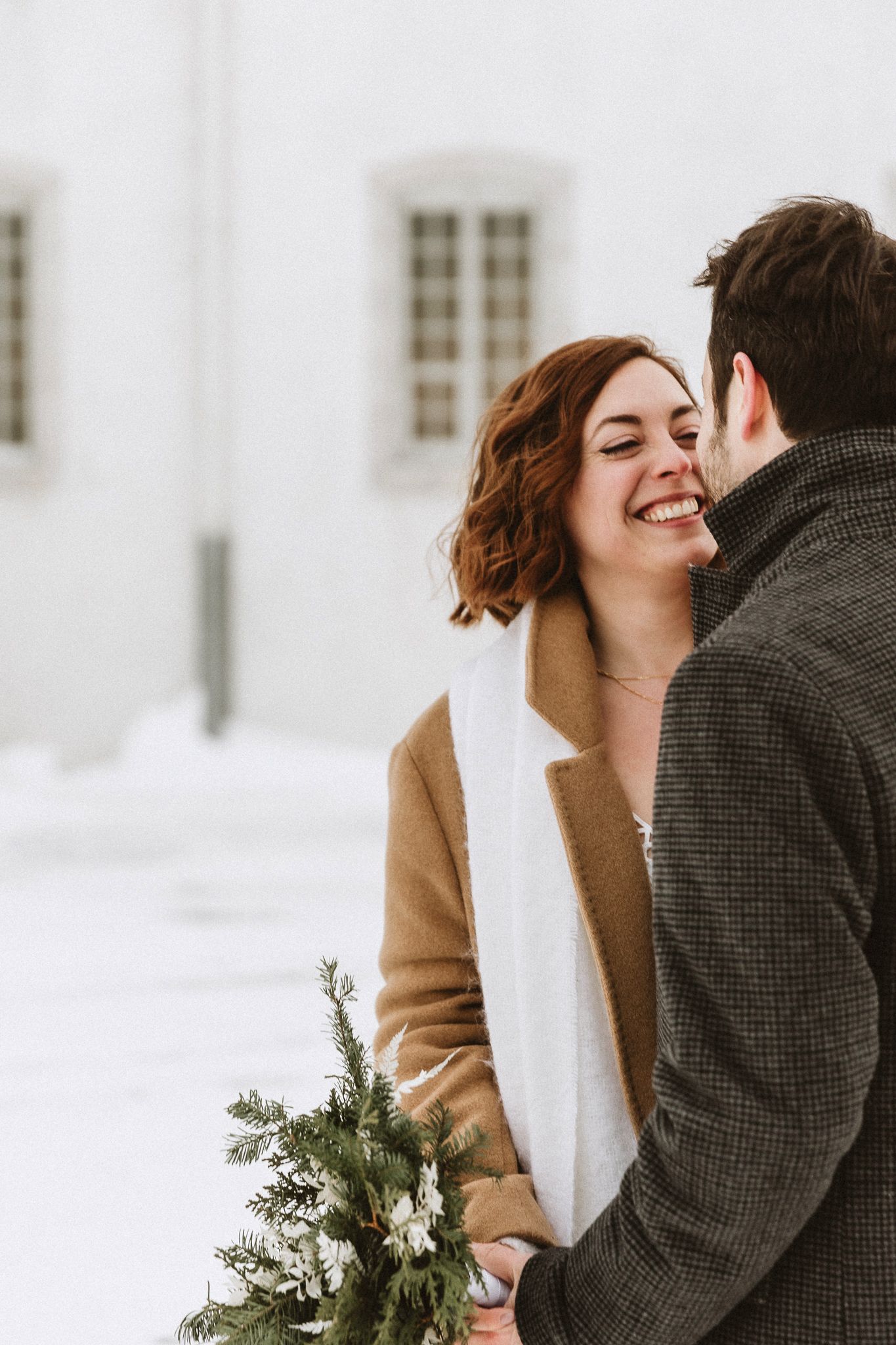 A winter wedding portrait showing couple sharing a tender moment outdoors in snow.