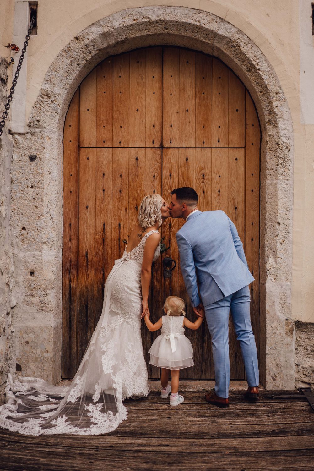 Wedding couple exploring a rustic wooden door entrance at a historic stone building.
