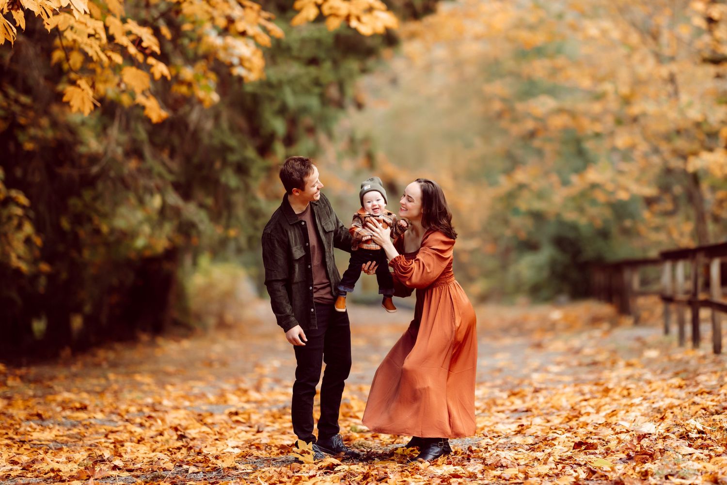 A family plays together in a park surrounded by fall foliage.