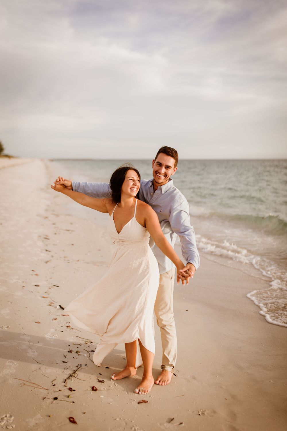 A couple dancing on Nokomis Beach in Nokomis, Florida for their engagement session at sunset time.