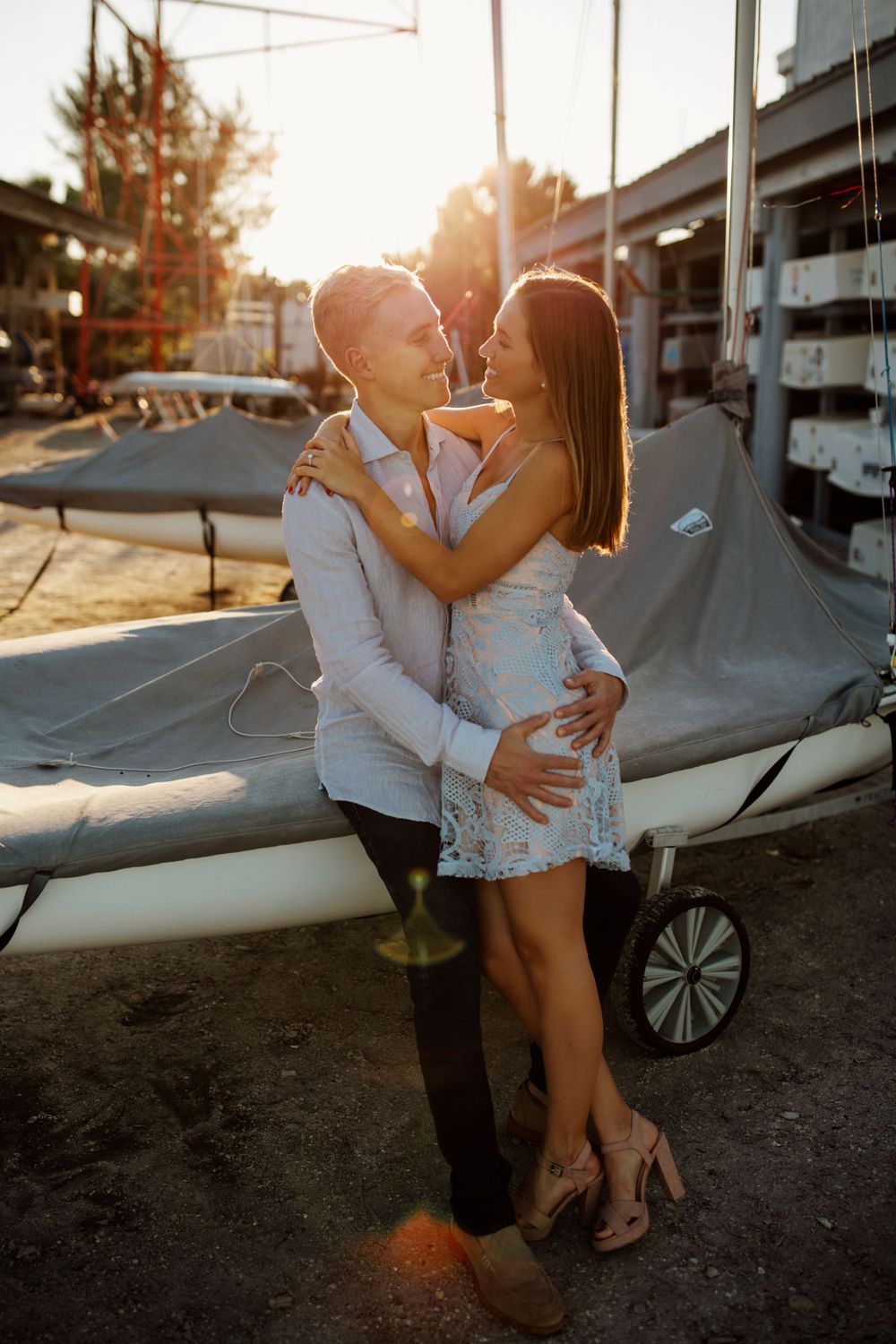 Engagement session couple hugging and smiling at sunset near sailboats in Longboat Key, Sarasota, Florida.