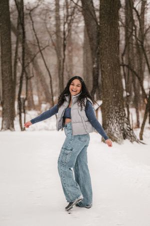 "Avon Lake High School graduate smiles amid snowfall, looking back with joy. Picture captured at Avon Lake nature trail.