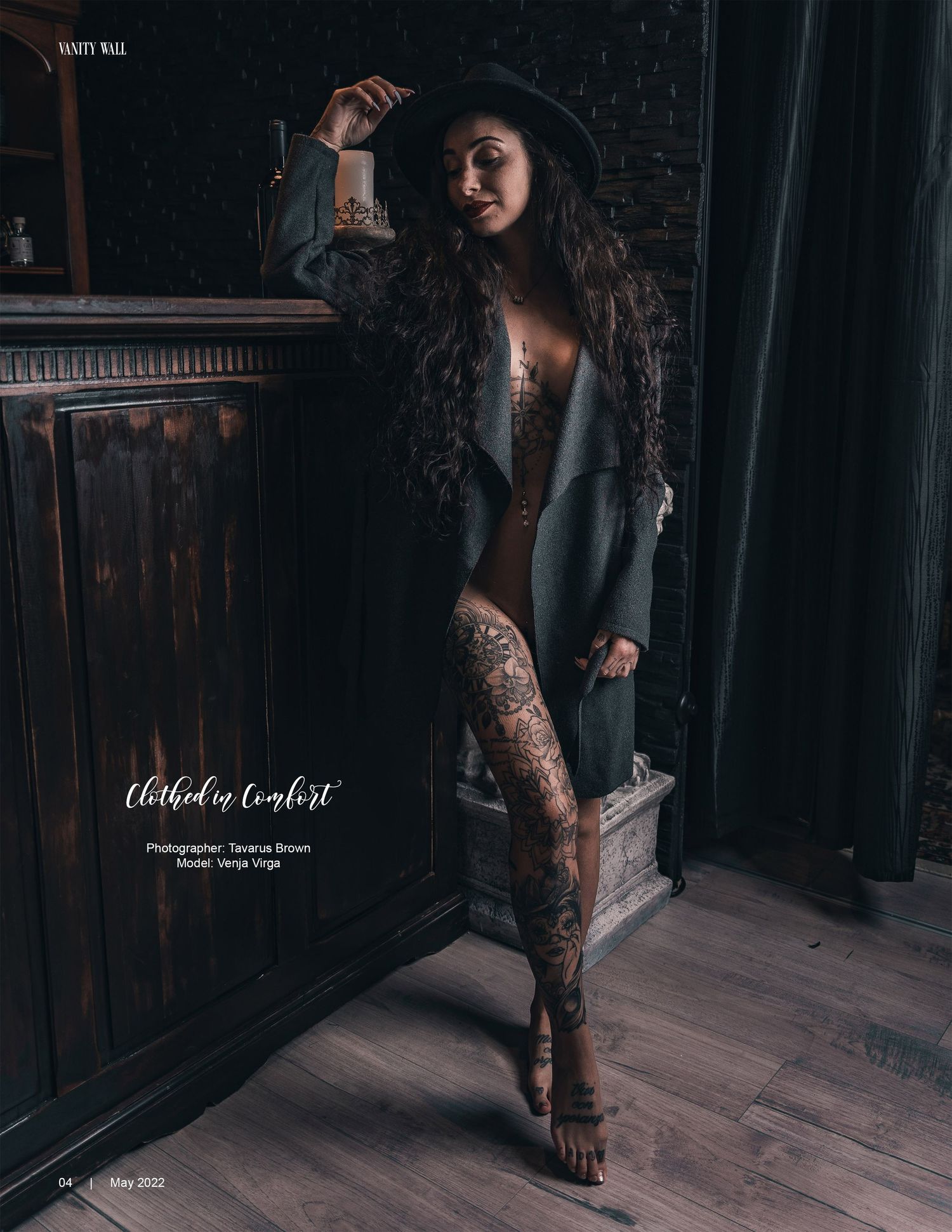 Dramatic portrait of a model in lingerie and blazer posing against dark wood paneling in moody lighting.