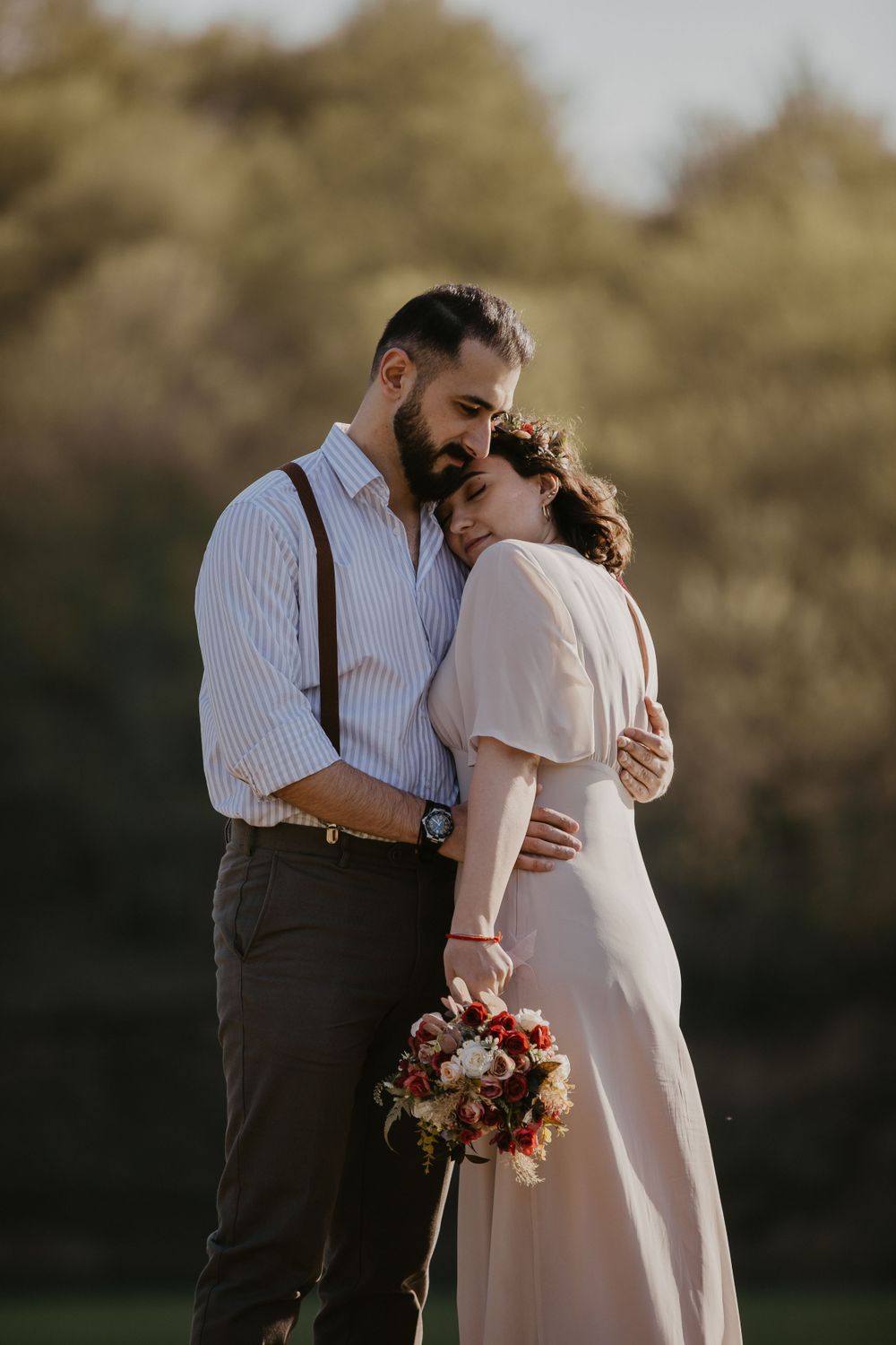 A couple embraces tenderly in vintage-inspired attire during a sunset photoshoot.