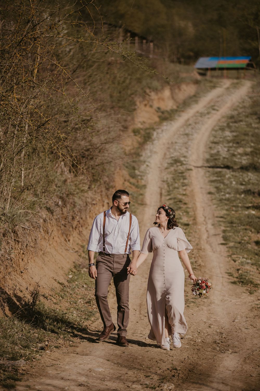 A couple strolls together along a winding country path during a rustic outdoor photo session.