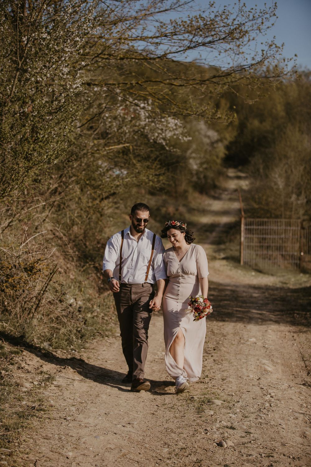 A couple walks together on a spring trail surrounded by blooming trees.