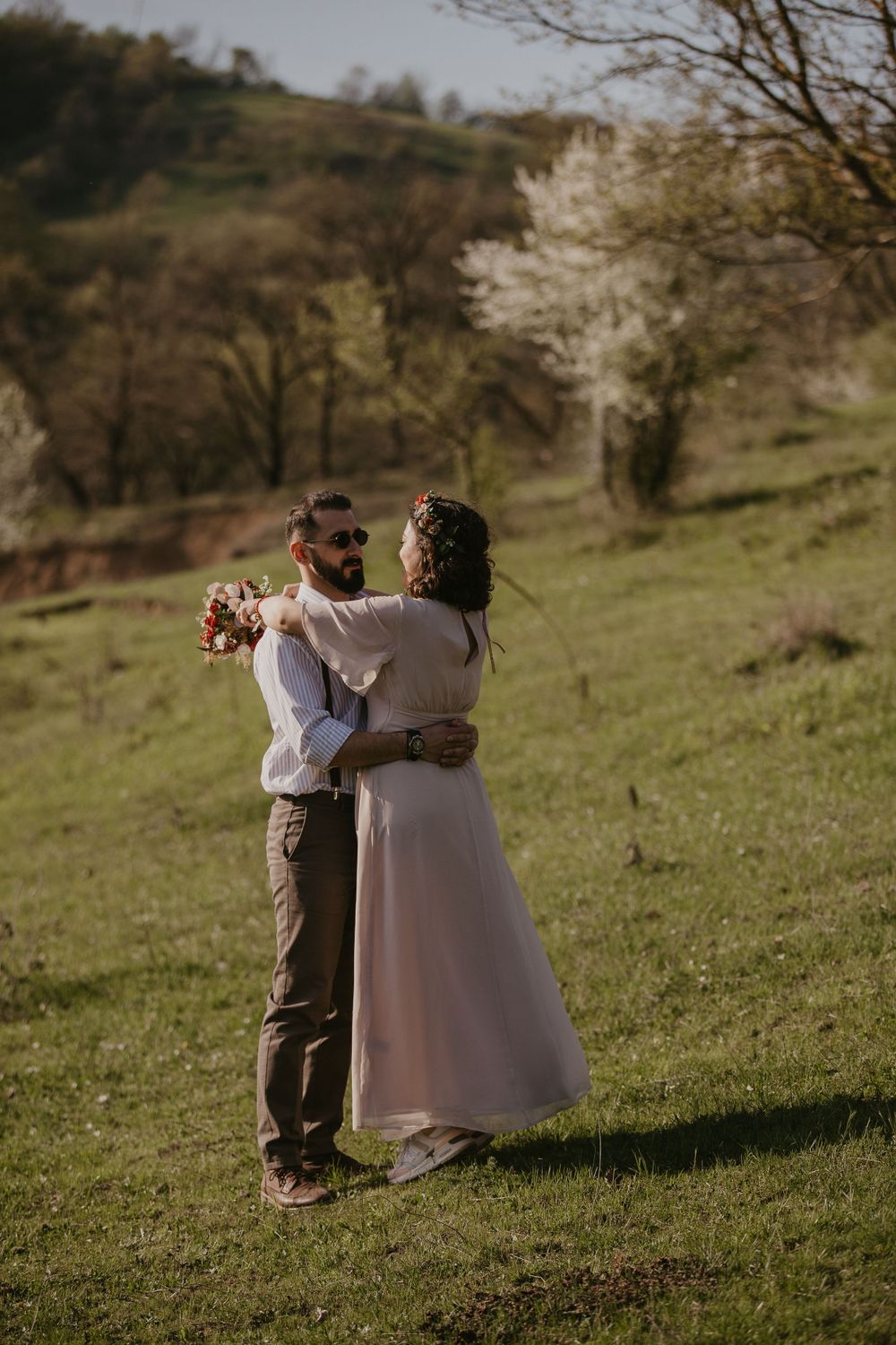 A tender moment shared between a couple on a green hillside in spring.