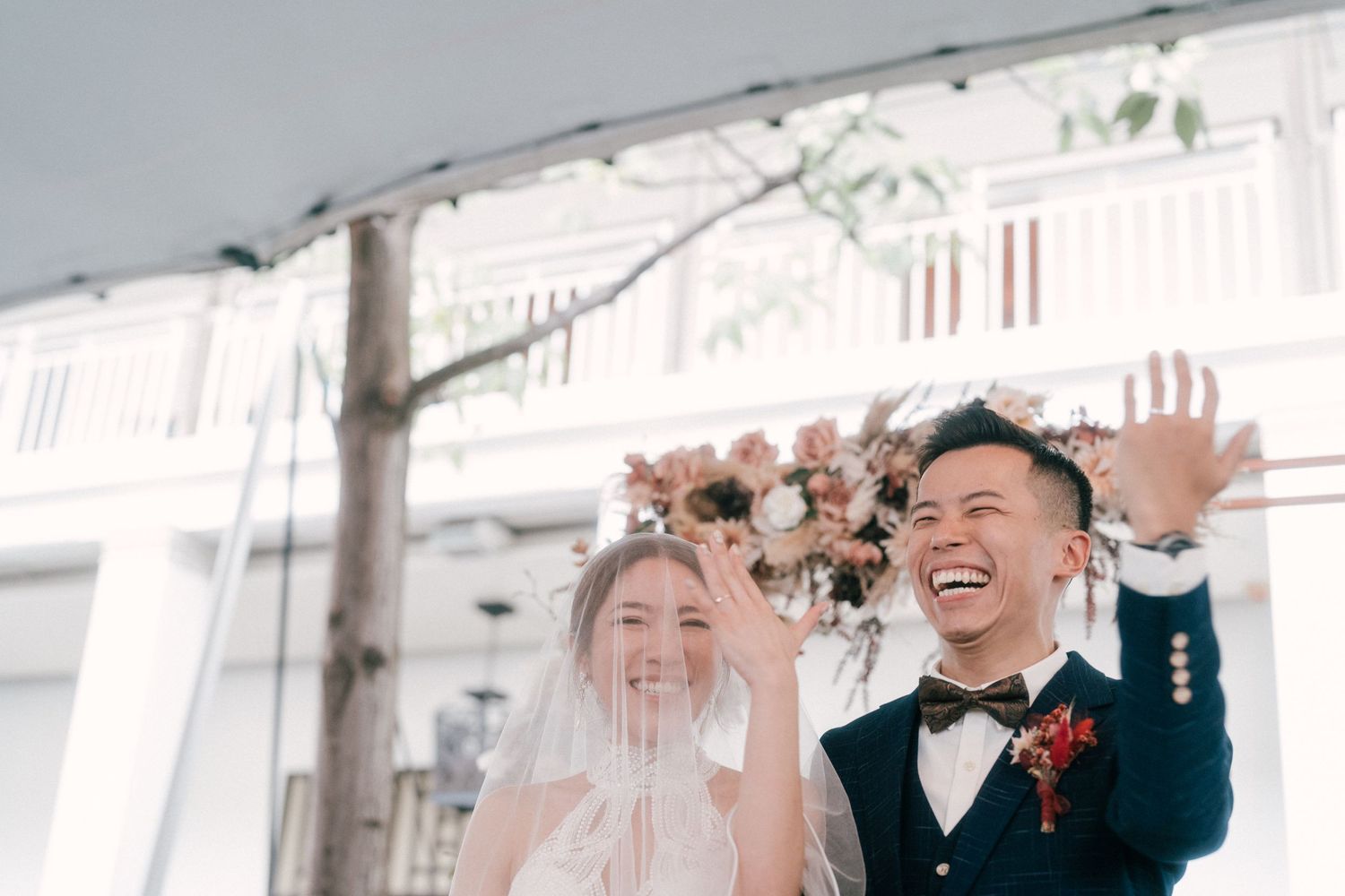 Joyful wedding moment captured against white background with floral decorations.