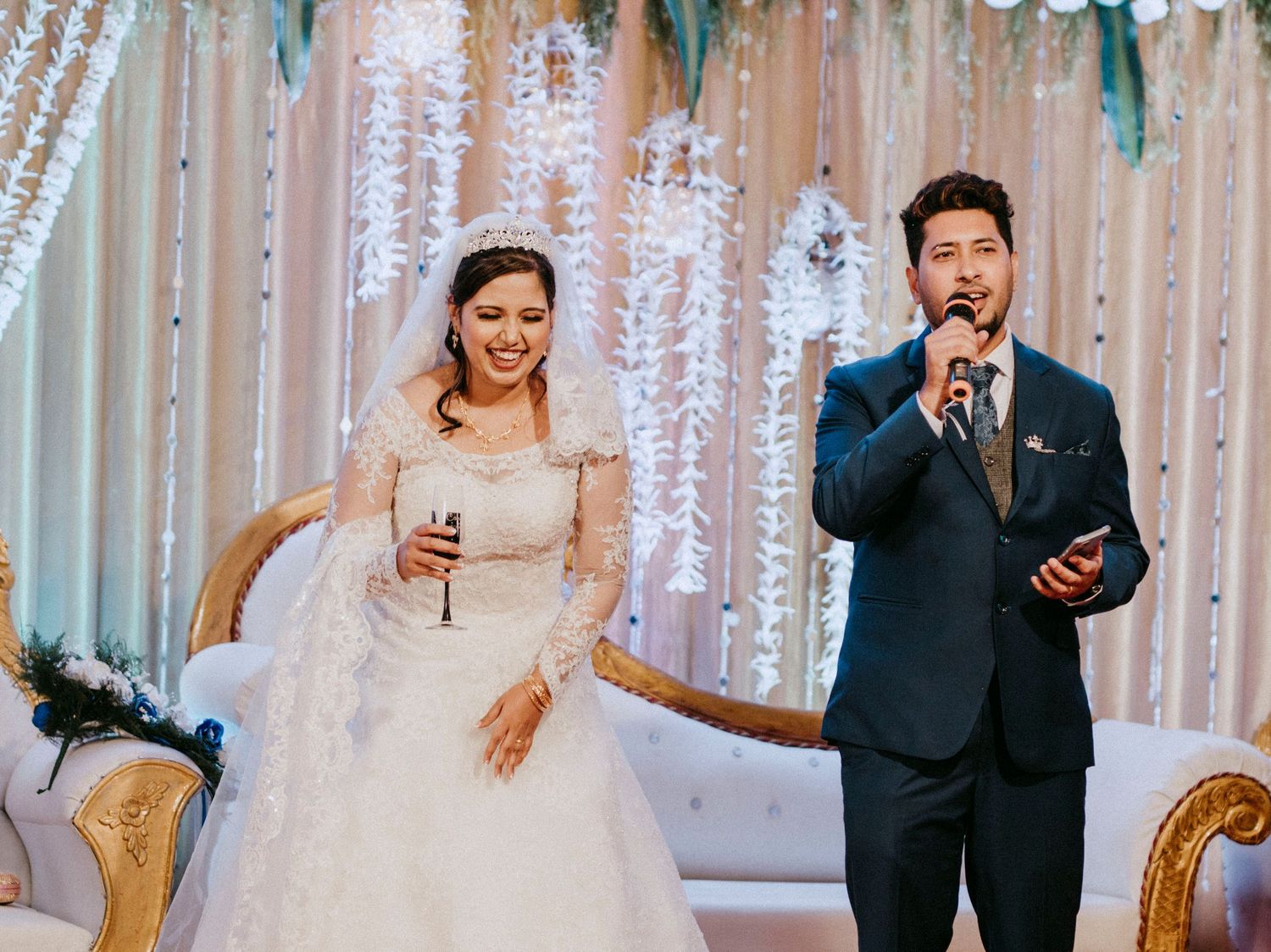Wedding couple shares laughter while looking at a phone during their reception.