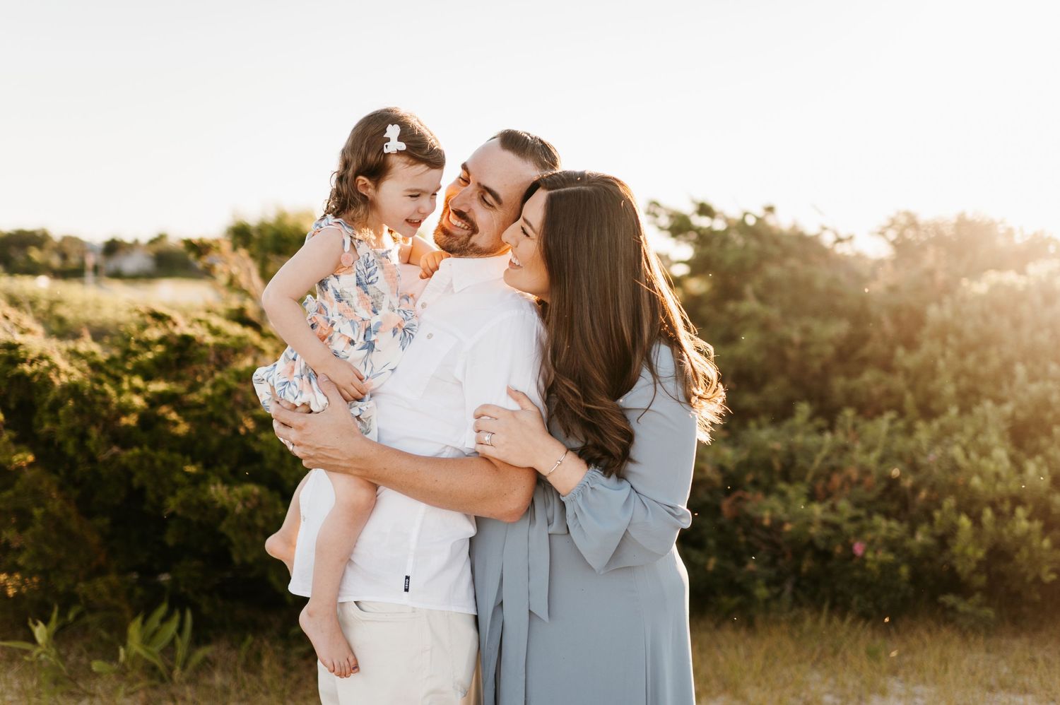 Family sharing tender moment outdoors during golden hour.