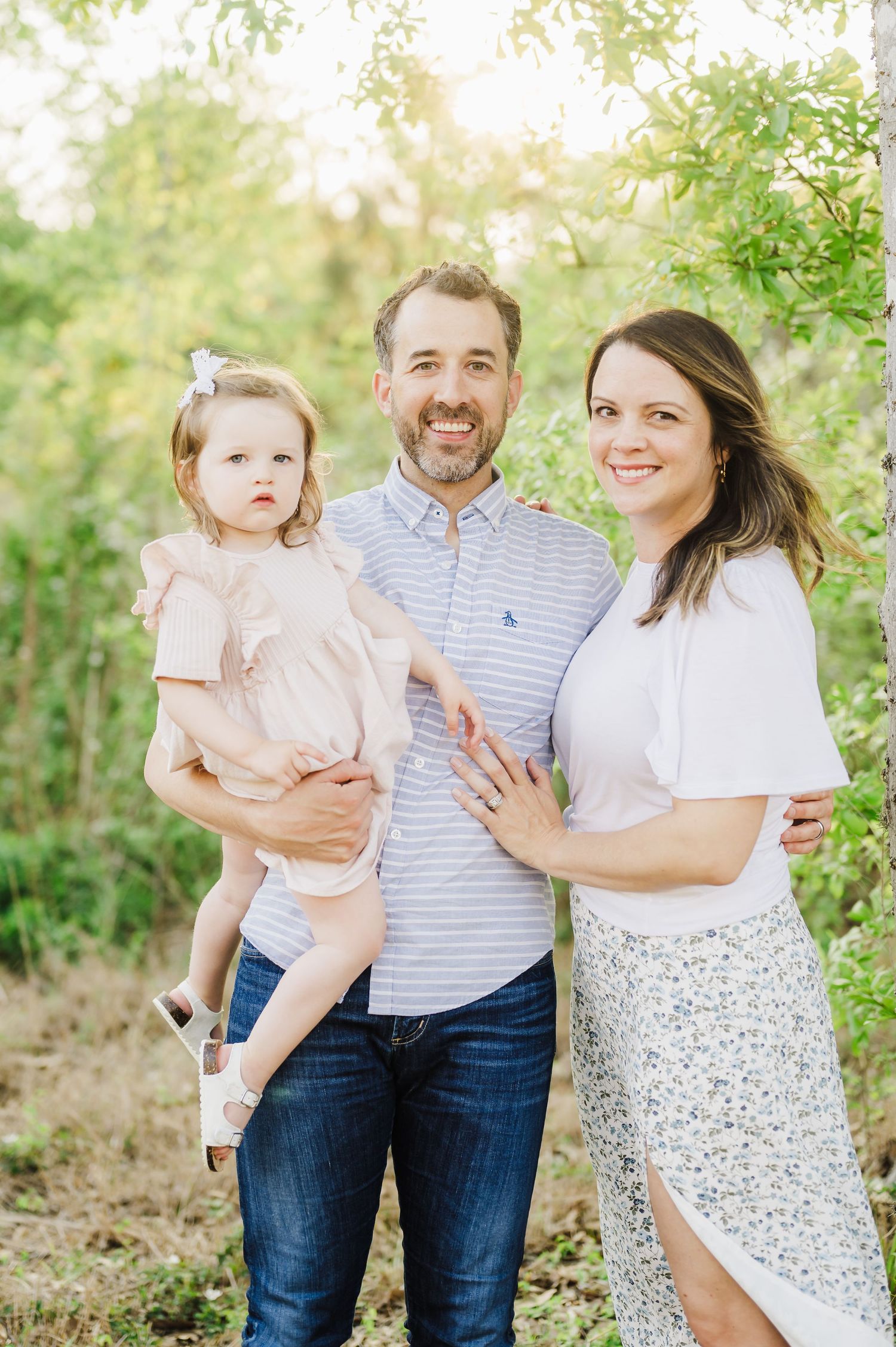Natural light family portrait in a lush green park setting.