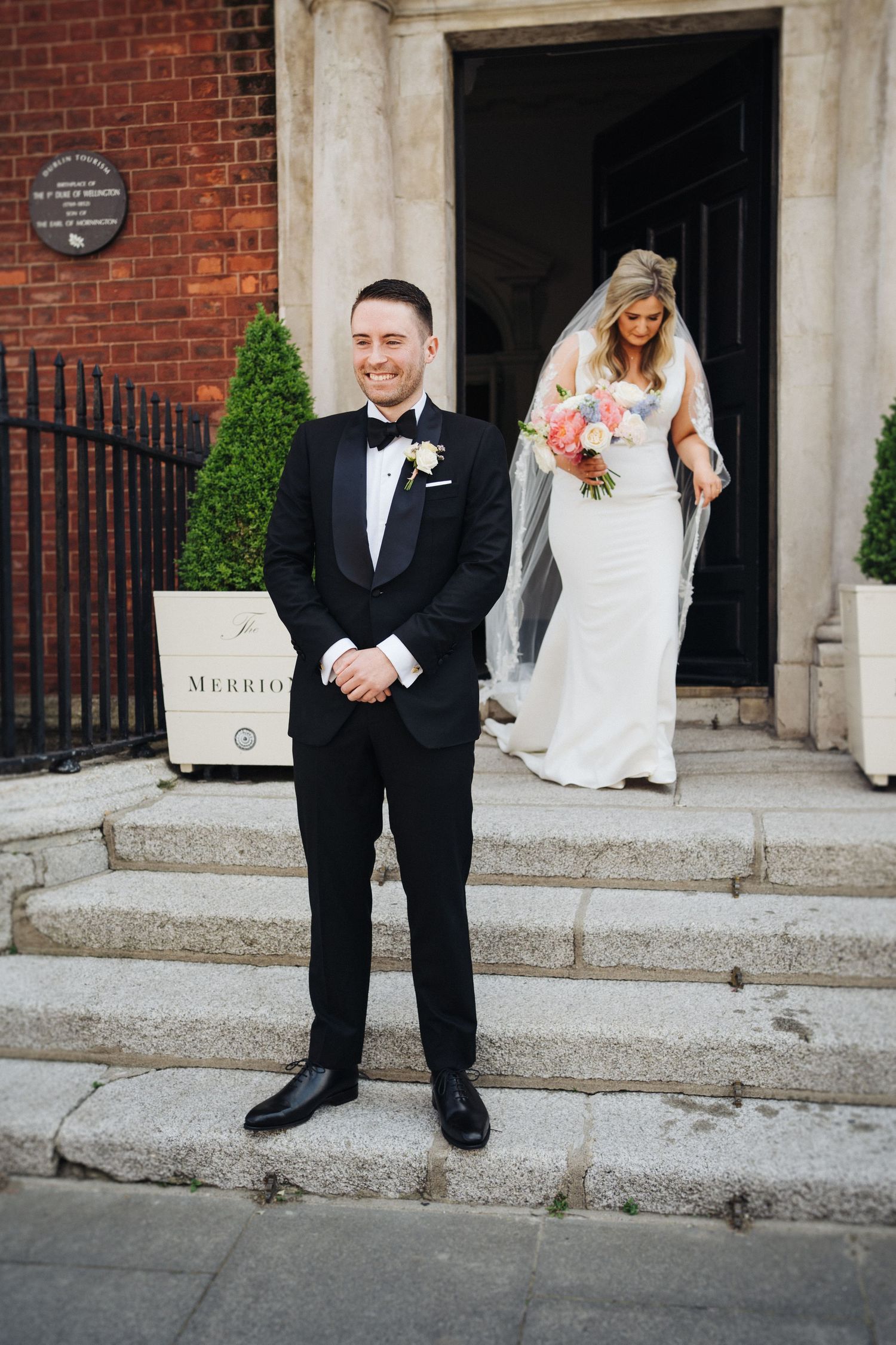 Classic first look setup with groom waiting on steps as bride approaches.