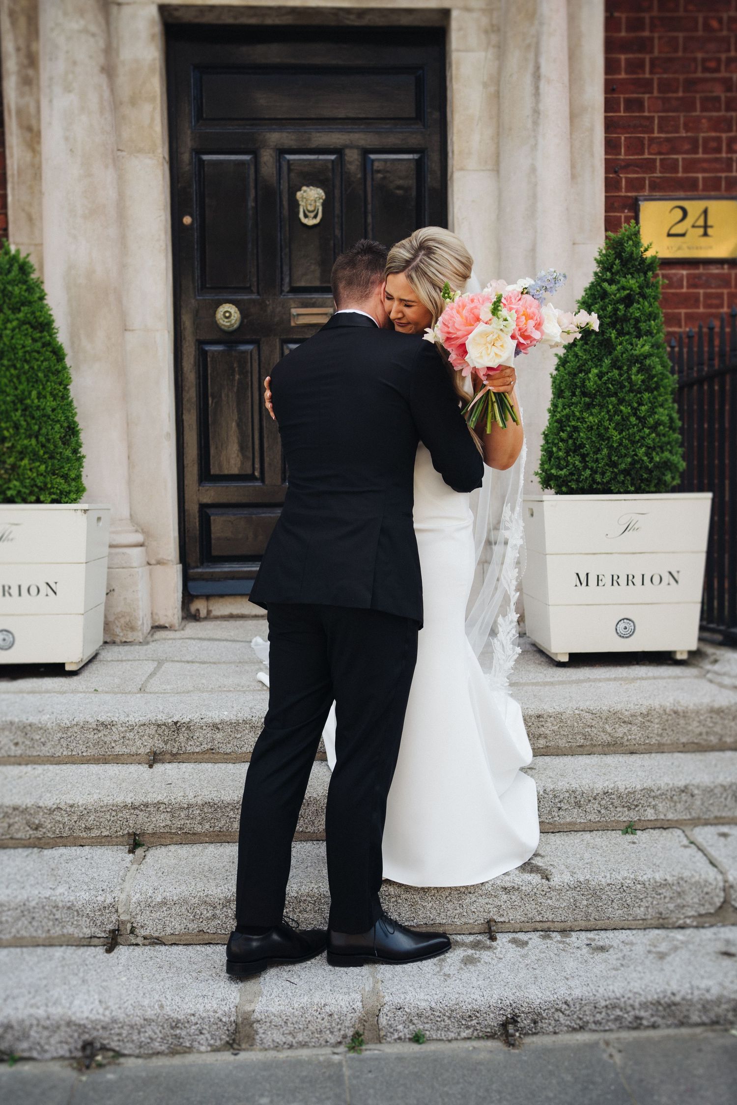 Intimate moment between newlyweds on stone steps of brick building.